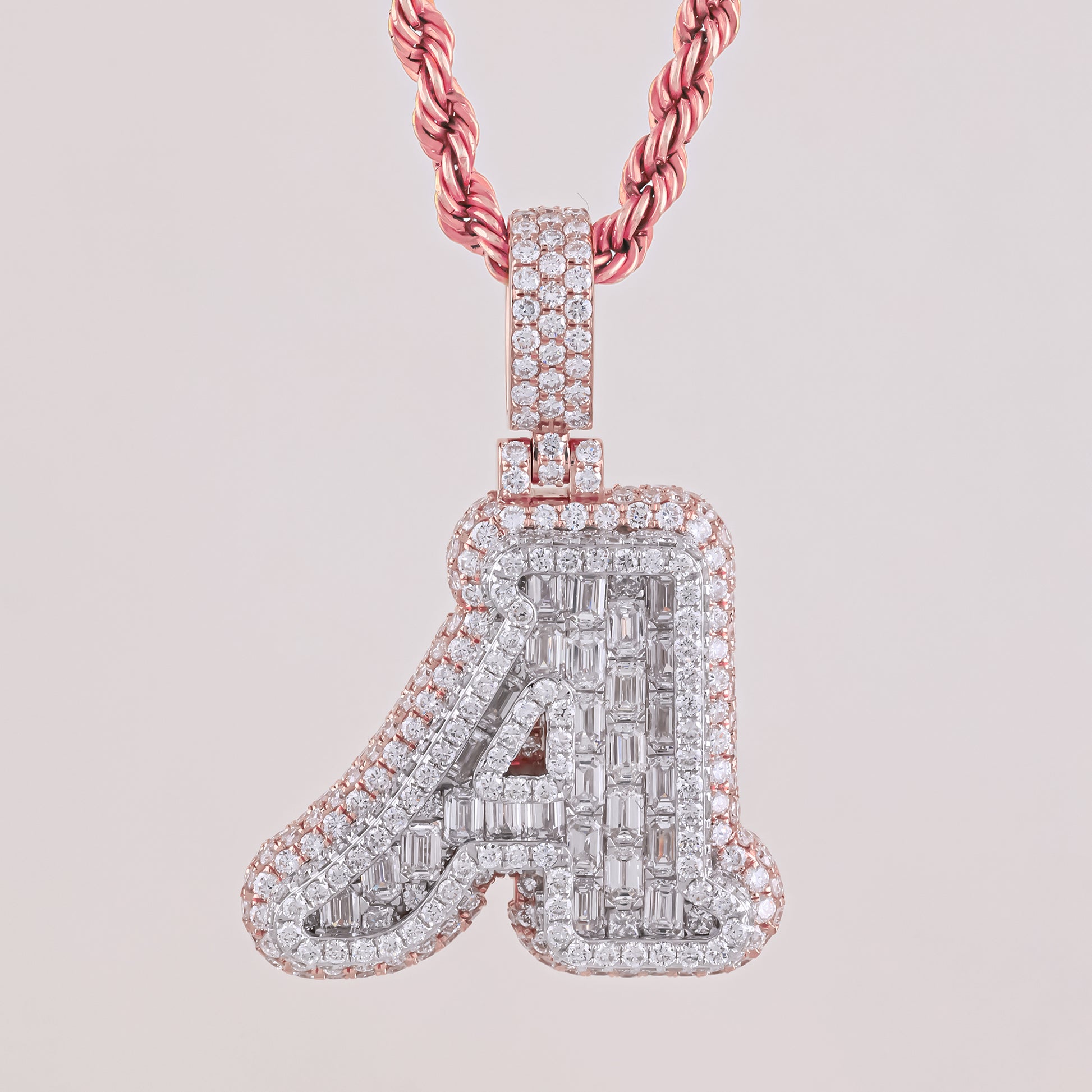 Diamond-studded letter 'A' pendant on a pink chain against a light pink background