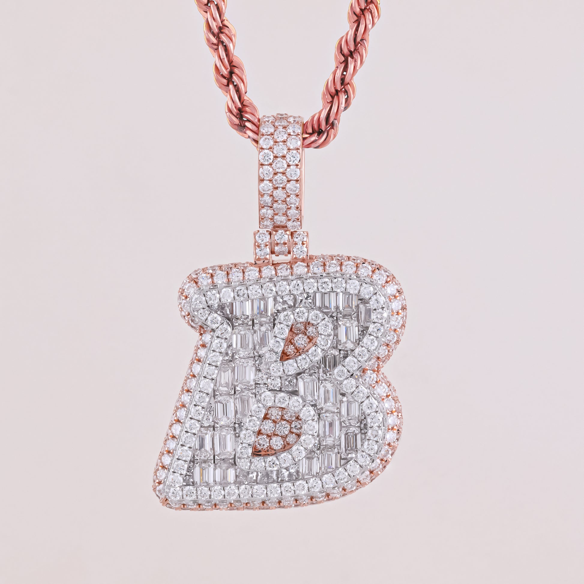 Diamond-encrusted letter 'B' pendant on a pink background
