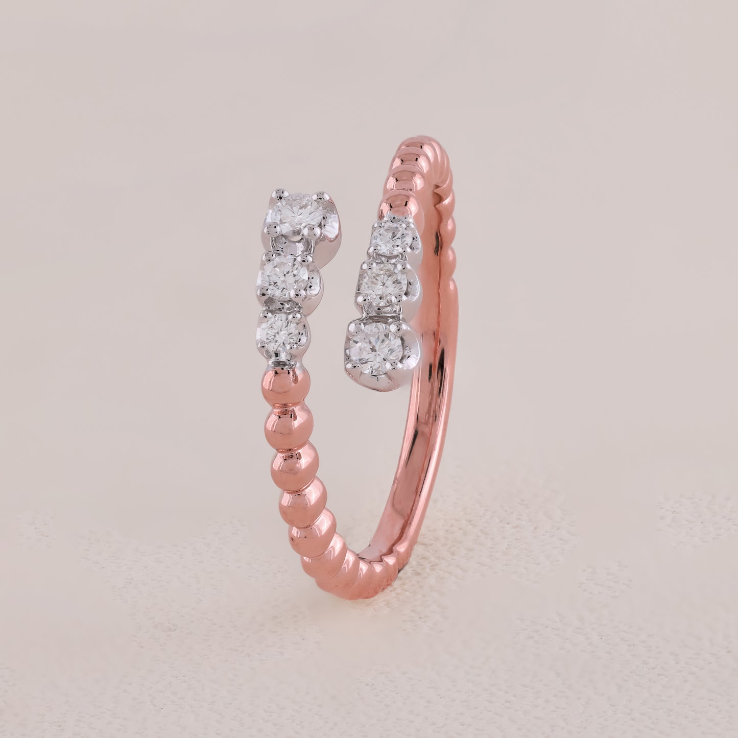 Rose gold ring with diamond accents on a light beige background