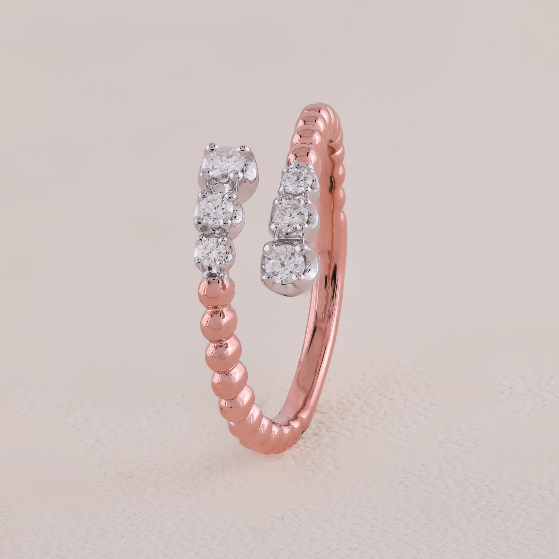 Rose gold ring with diamond accents on a light beige background