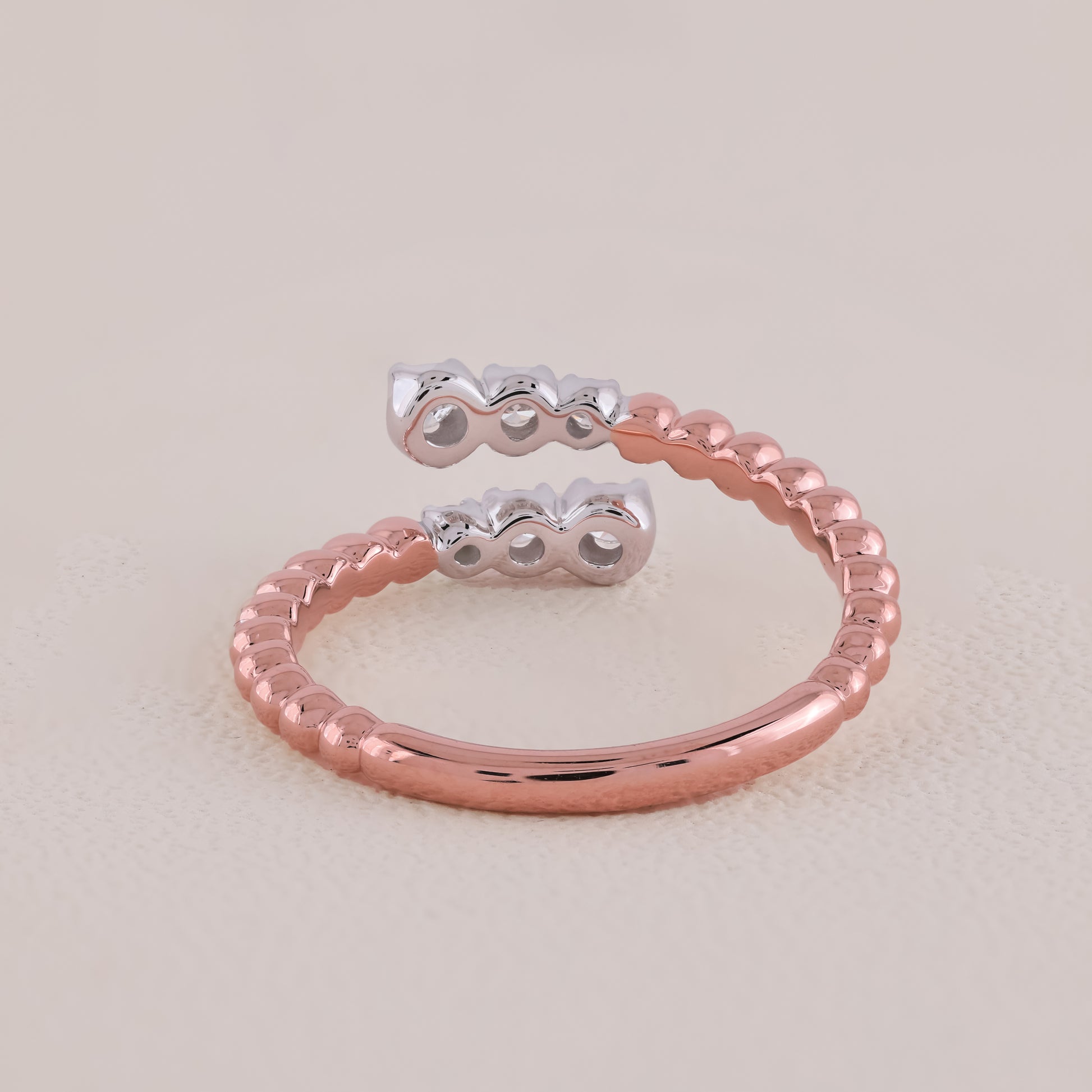 Two rings, one silver and one rose gold, on a light beige background