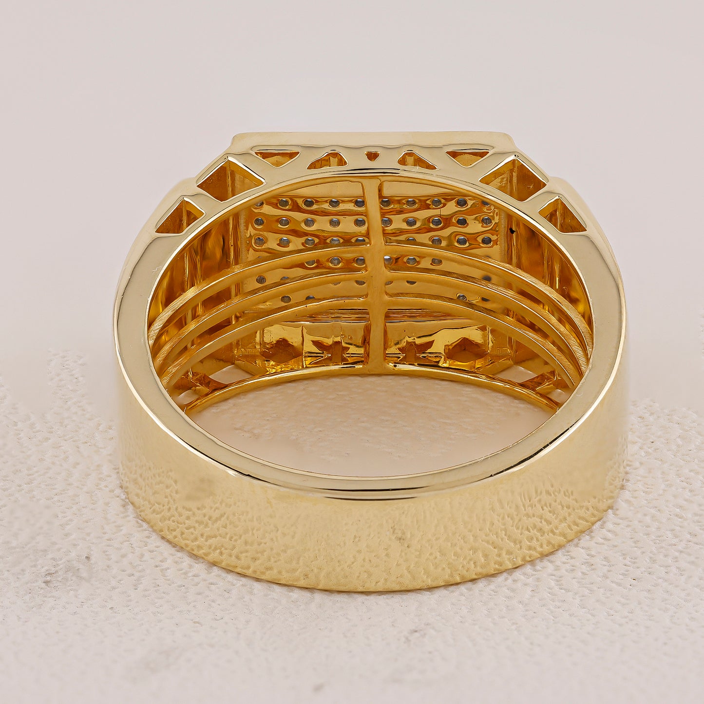 Gold ring with intricate design on a light gray background
