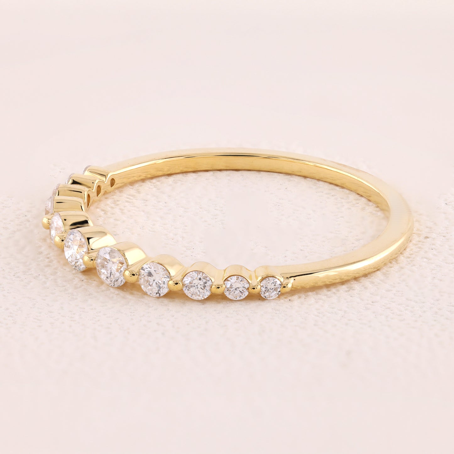 Gold ring with small diamonds on a light beige background