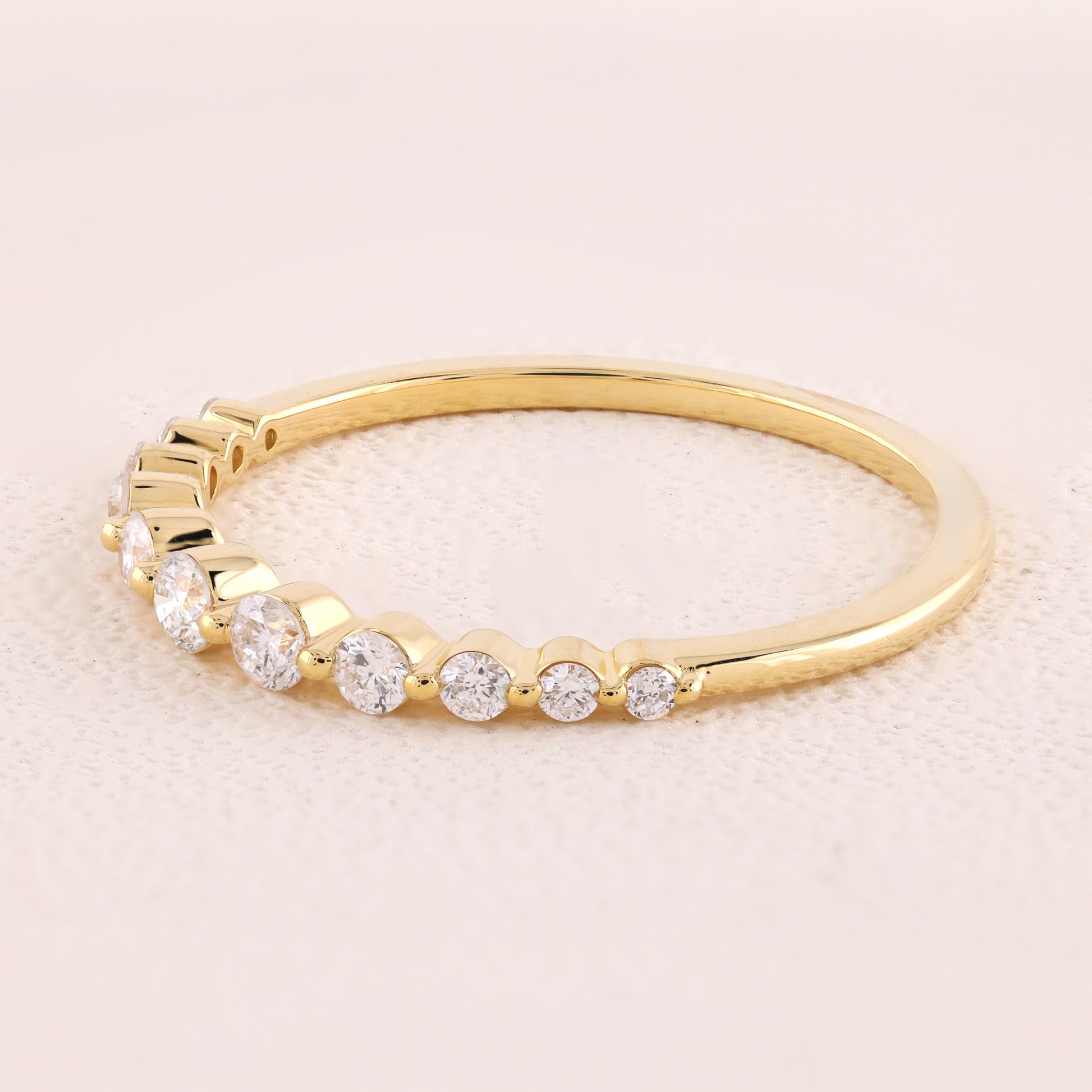 Gold ring with small diamonds on a light beige background