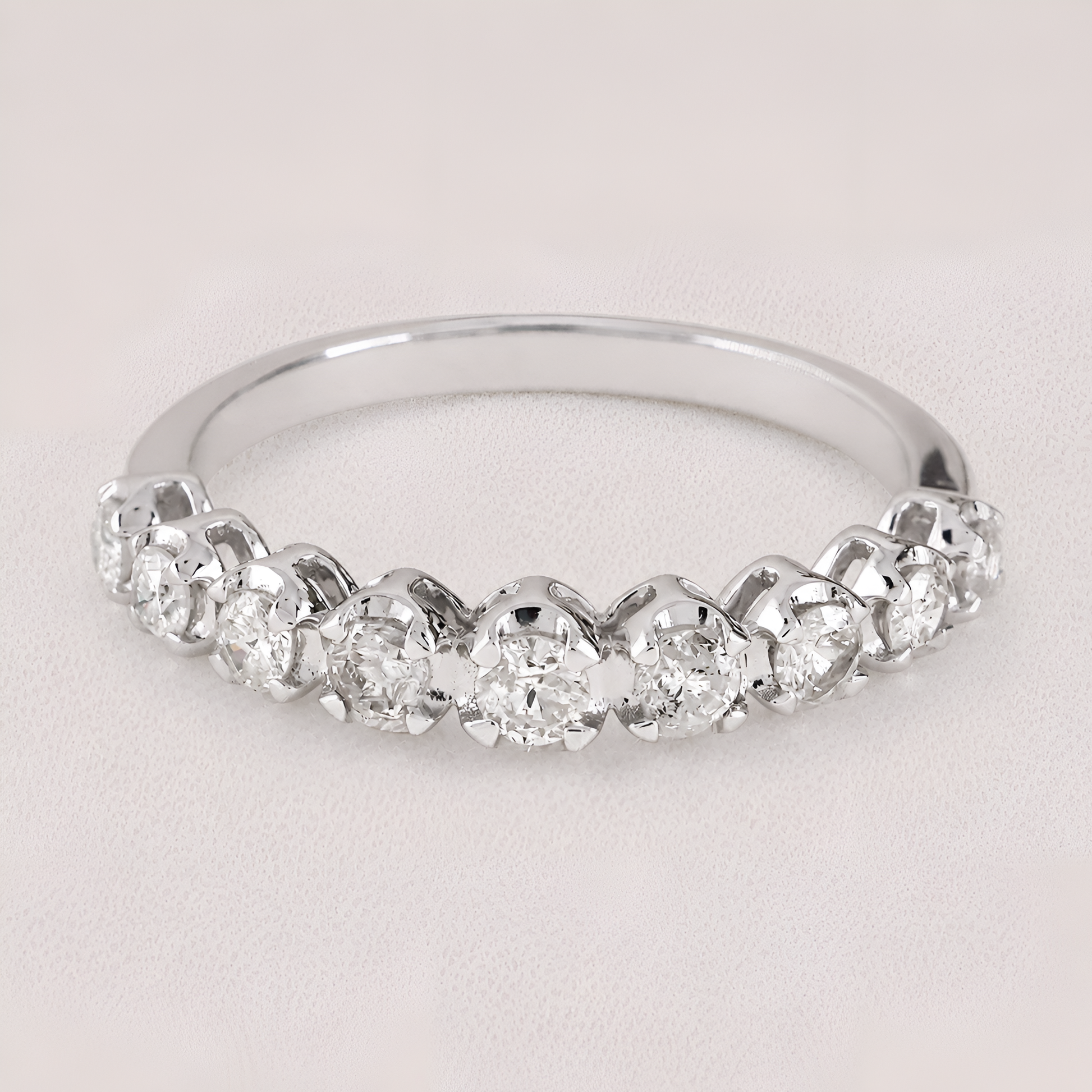 A silver-toned diamond band ring featuring a row of round-cut diamonds set in a half-circle arrangement, photographed on a light neutral background.