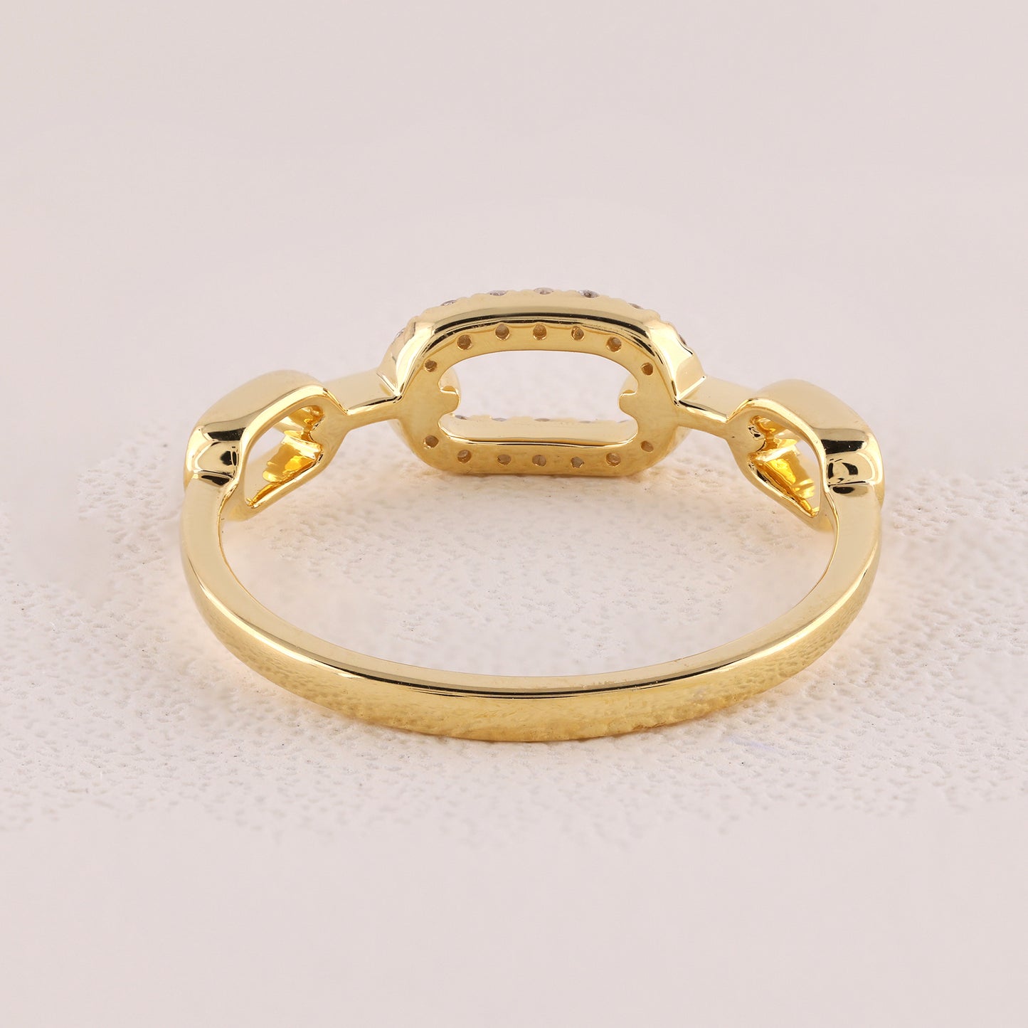 Gold ring with a unique design on a light pink background
