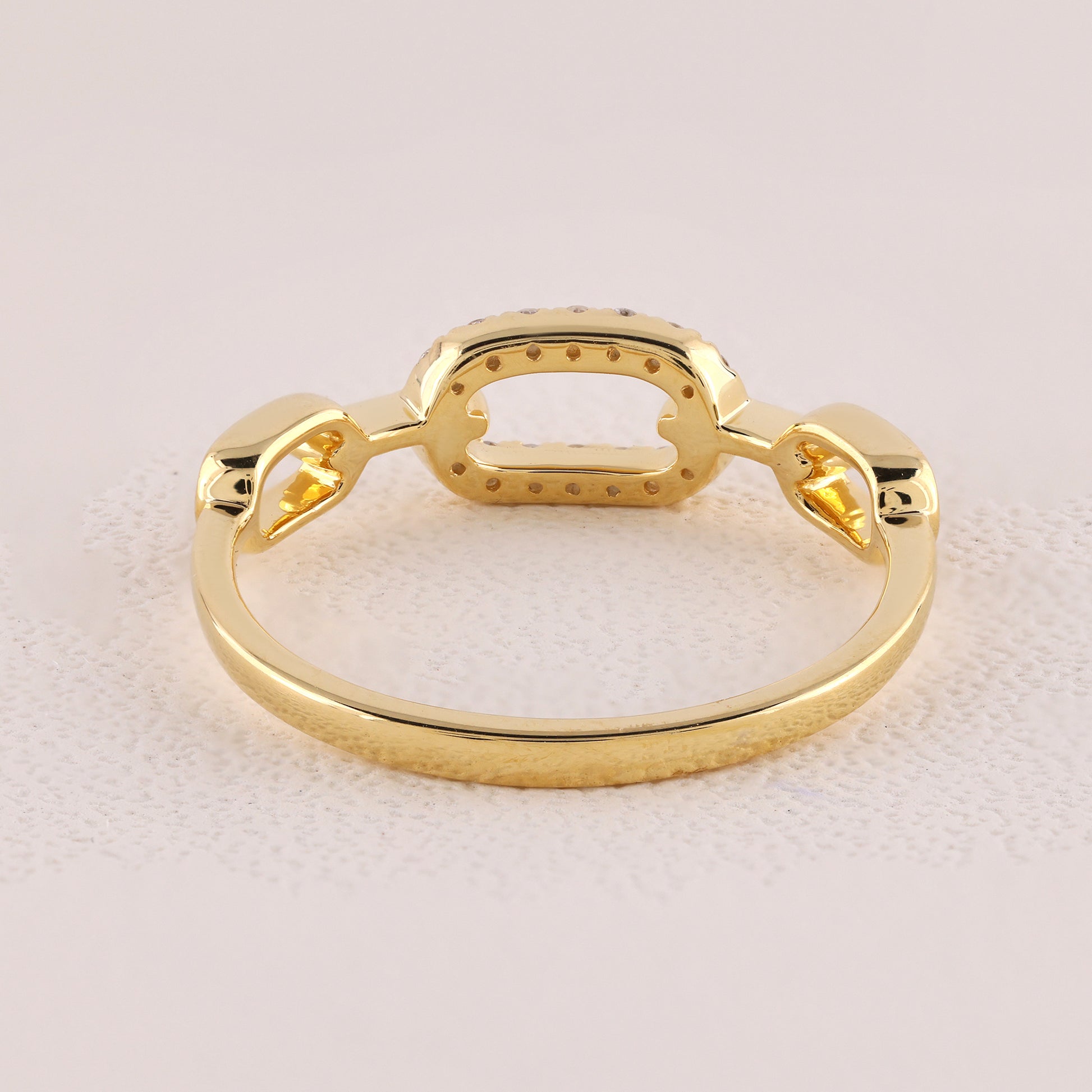 Gold ring with a unique design on a light pink background