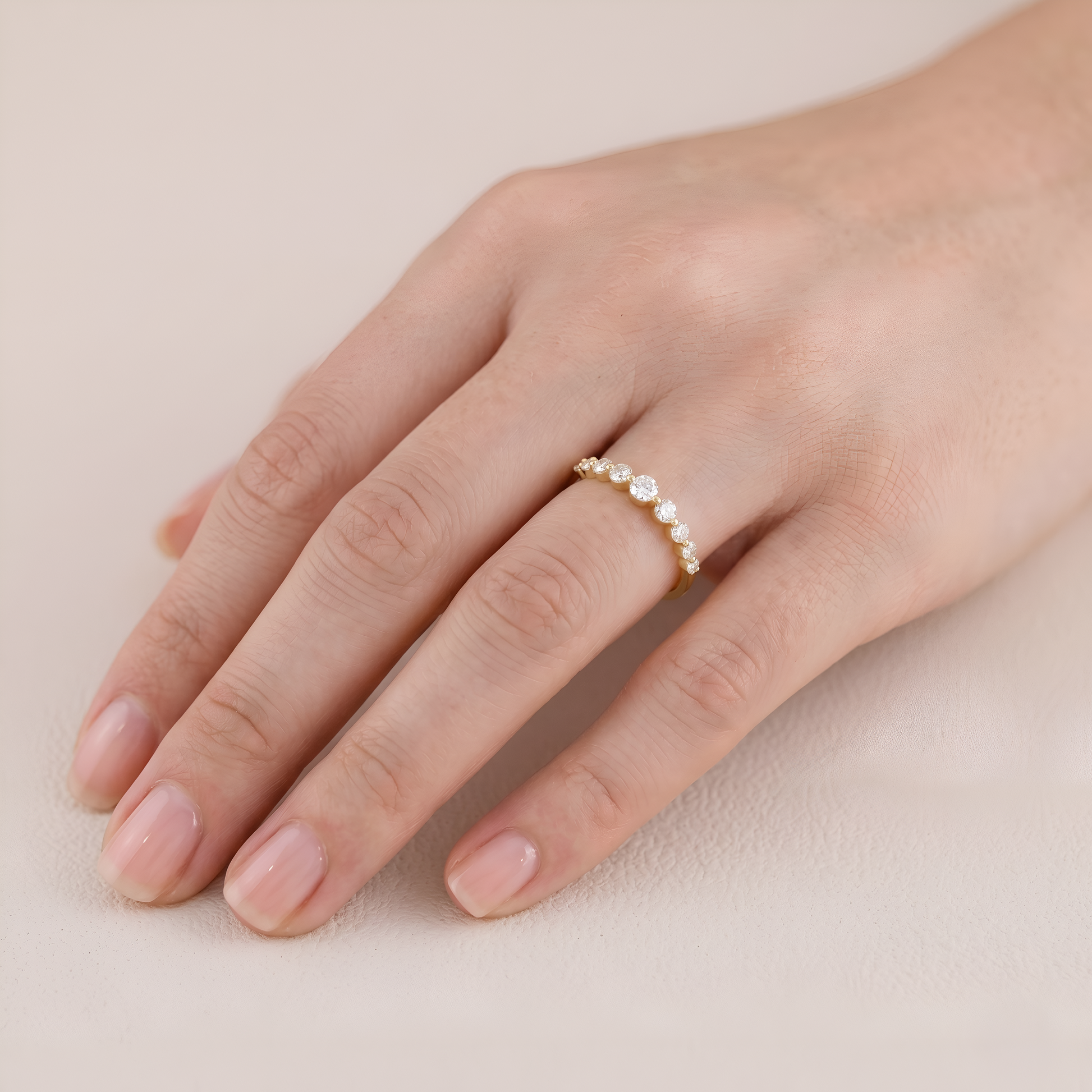 Close-up of a hand wearing a silver ring on a beige background