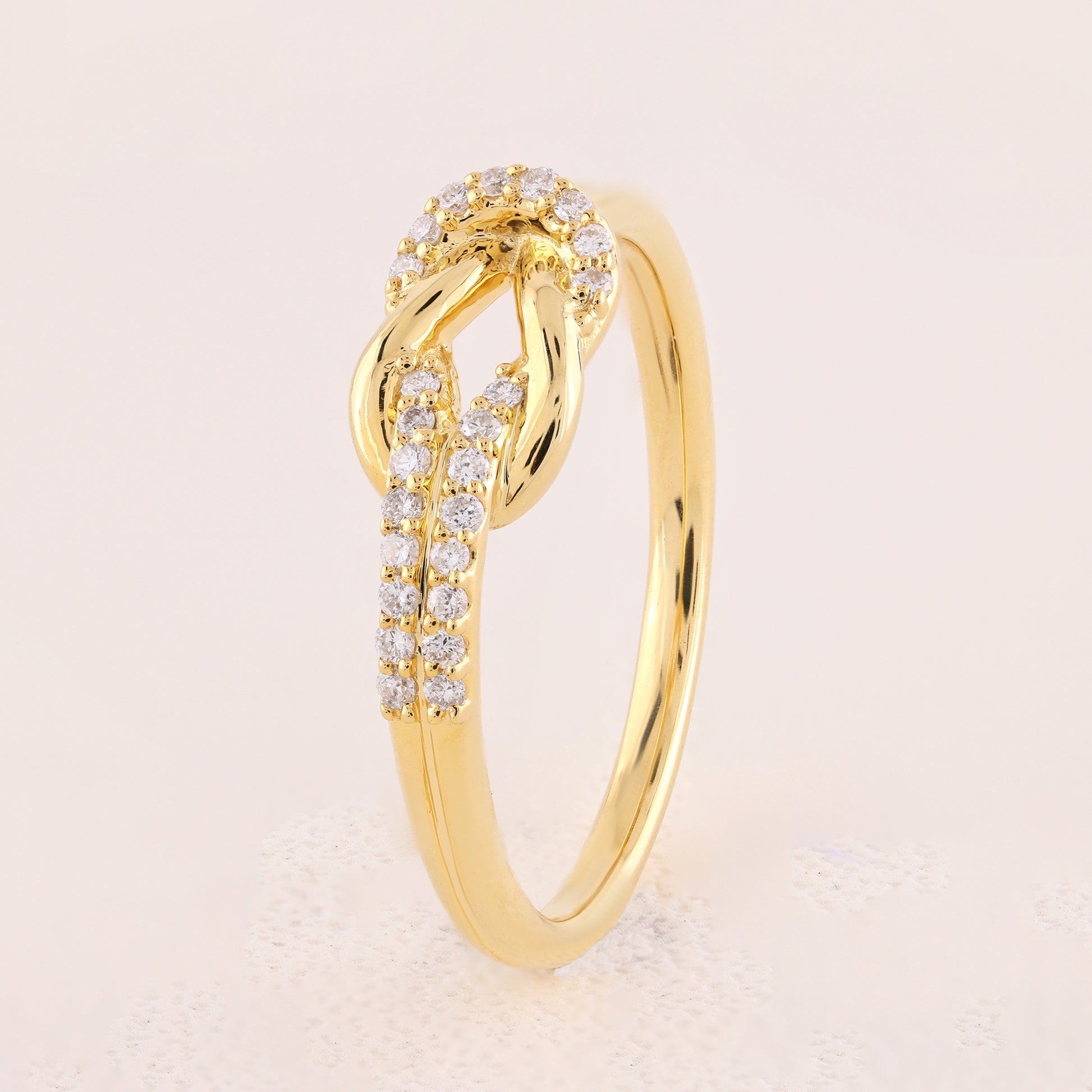 Gold ring with diamond accents on a light beige background