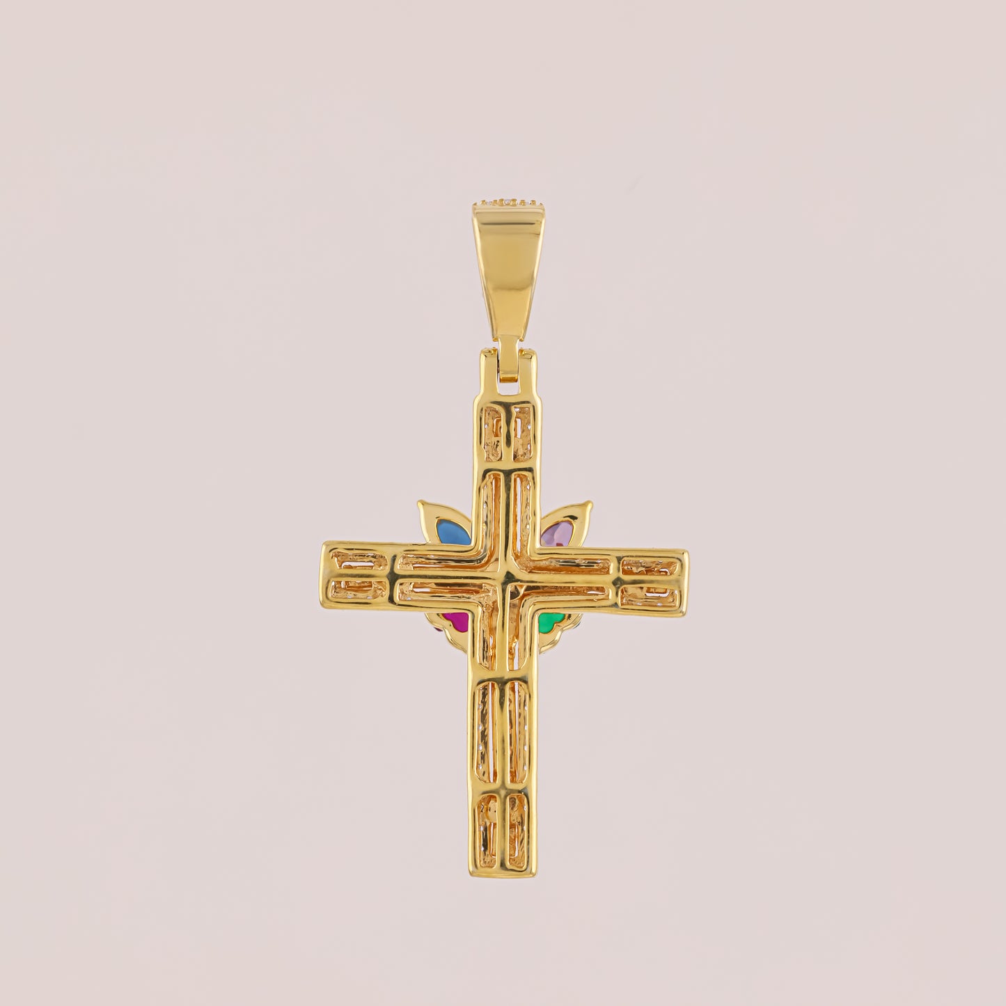 Gold cross pendant with colored stones on a beige background
