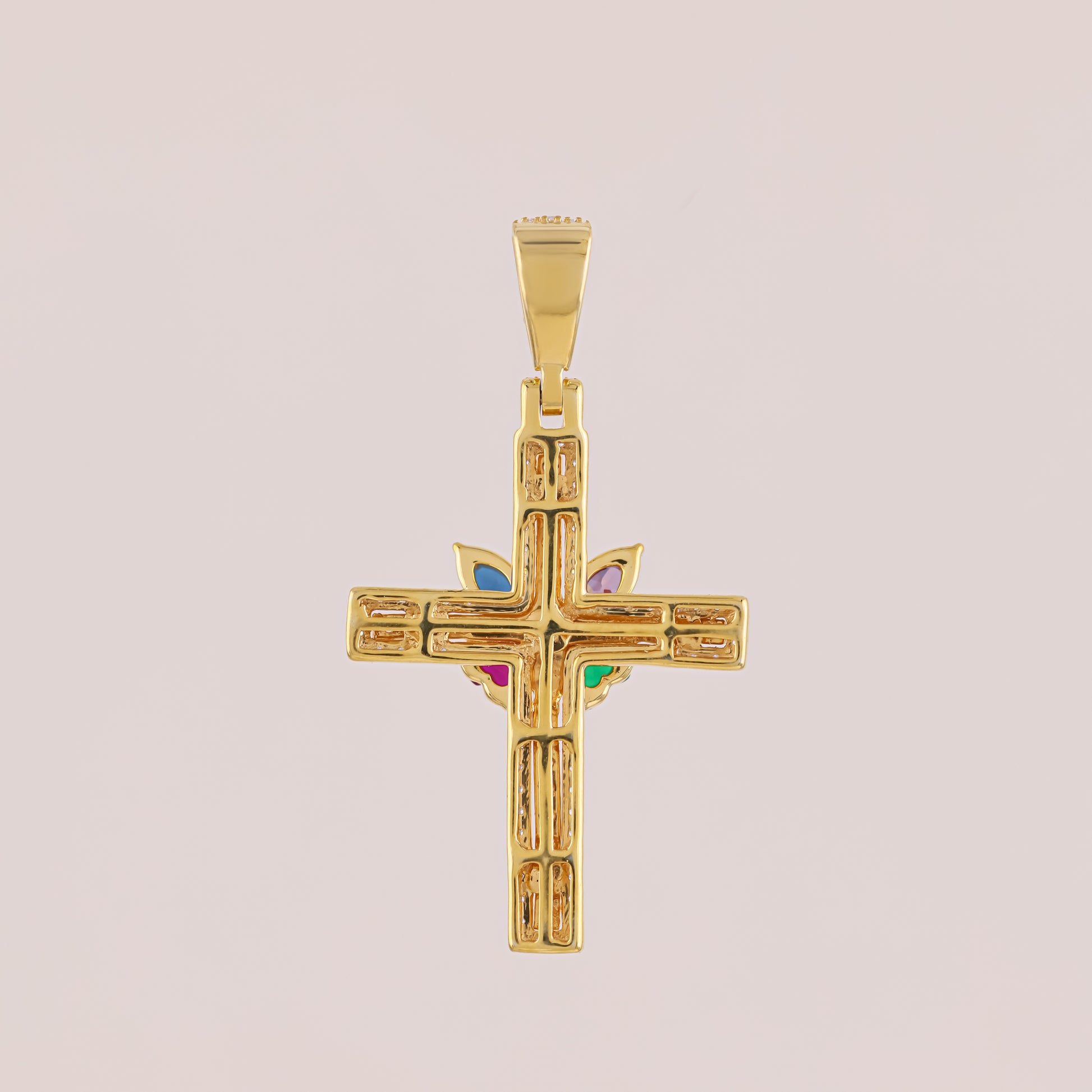 Gold cross pendant with colored stones on a beige background