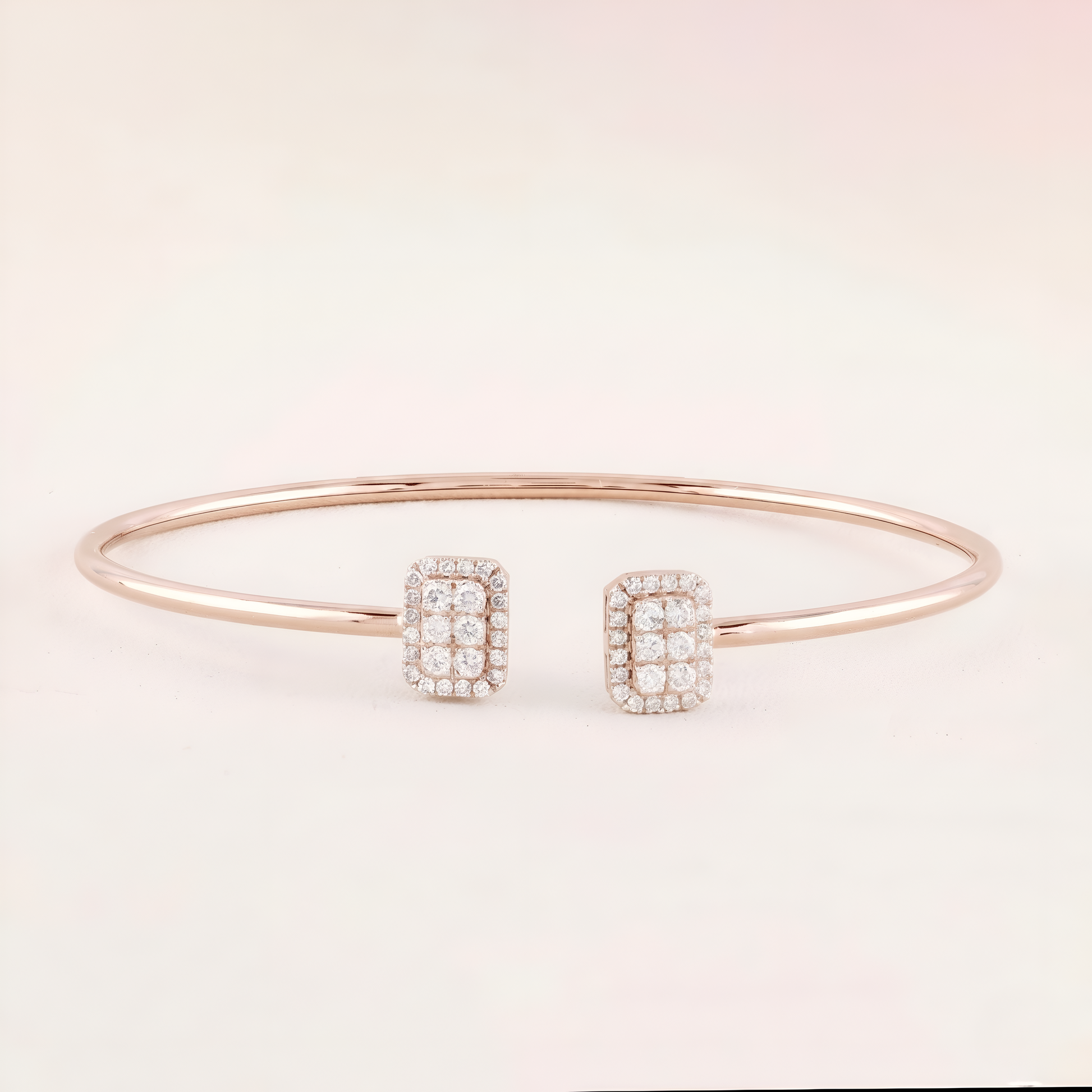 Rose gold bracelet with diamond-studded rectangular charms on a light pink background