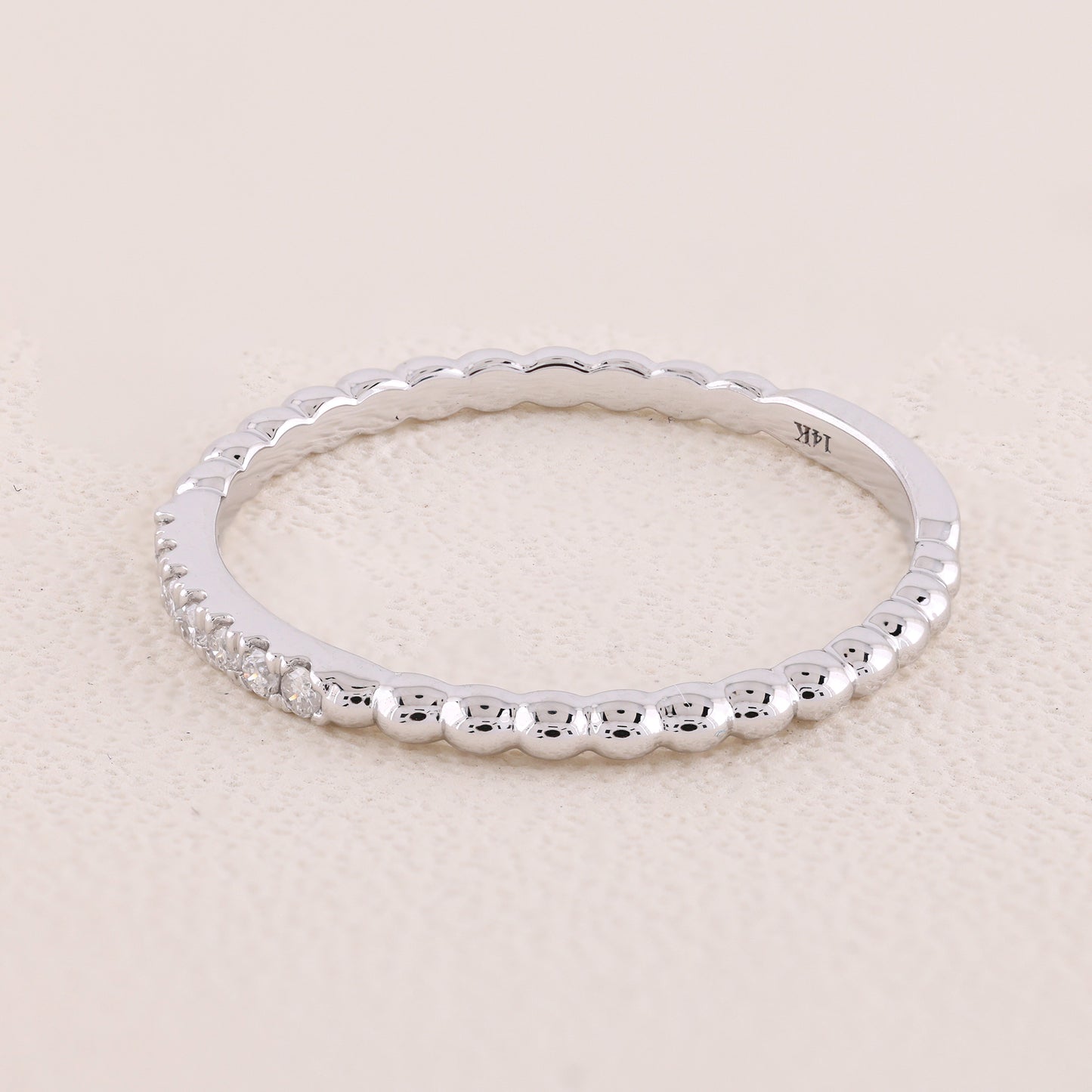 Silver ring with beaded design on a light beige background