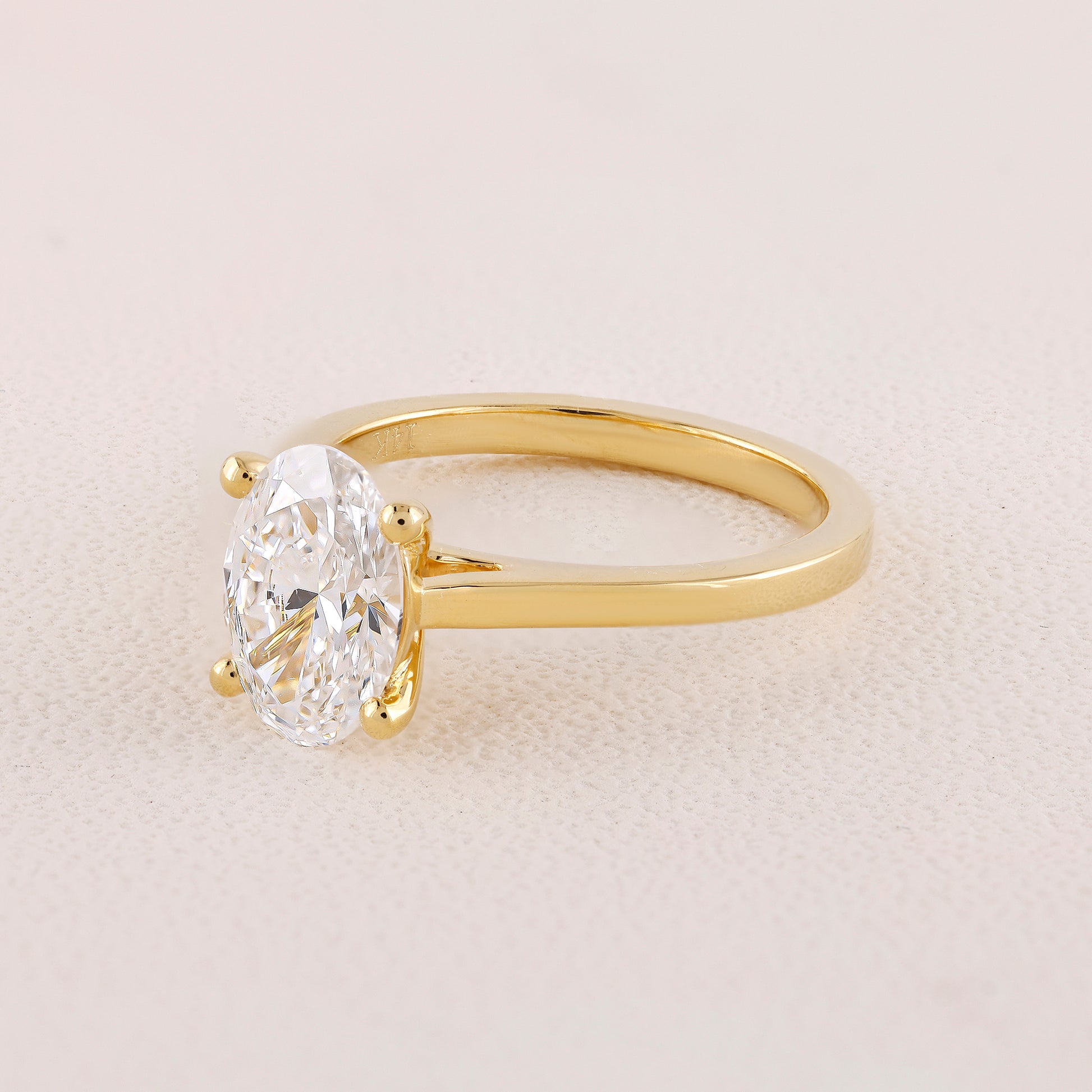 Gold ring with a large diamond on a light beige background