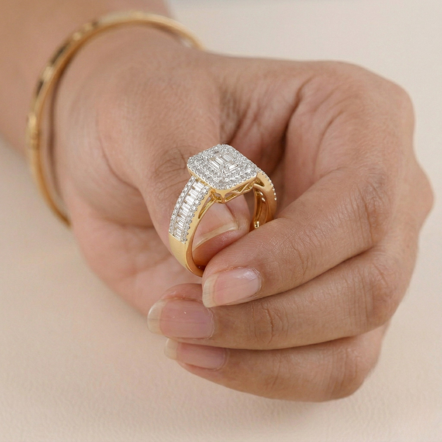 Gold ring with diamonds on a hand against a beige background