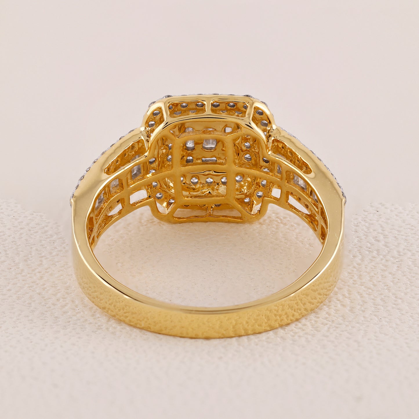 Gold ring with intricate design on a light beige background