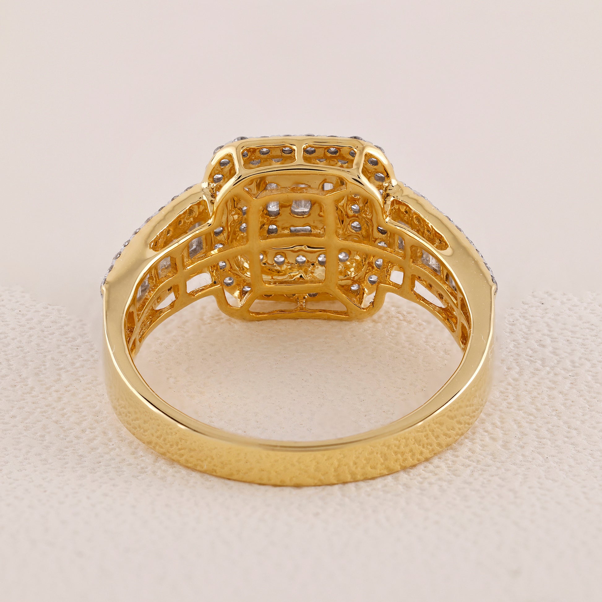 Gold ring with intricate design on a light beige background