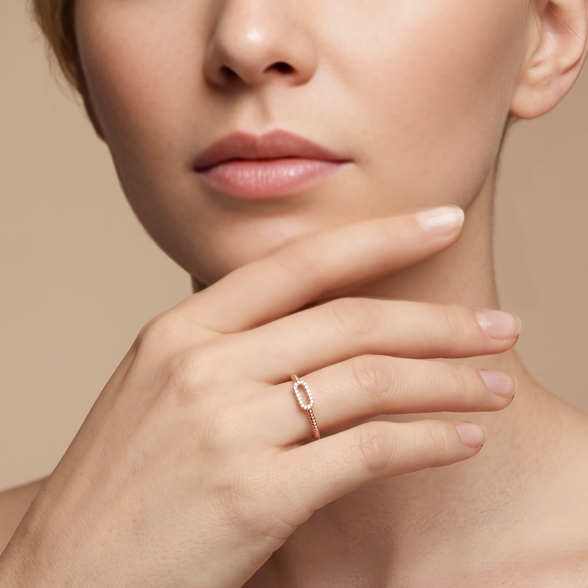 Close-up of a hand wearing a rose gold ring with a neutral background