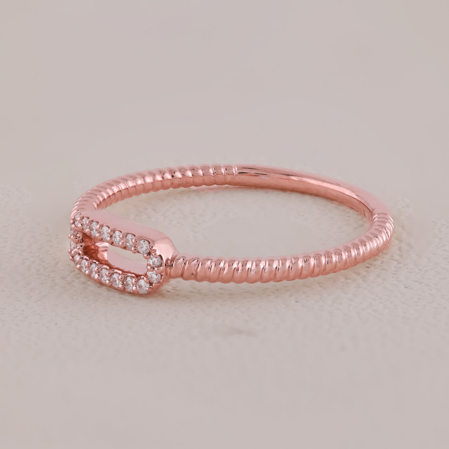Rose gold ring with small diamonds on a light beige background