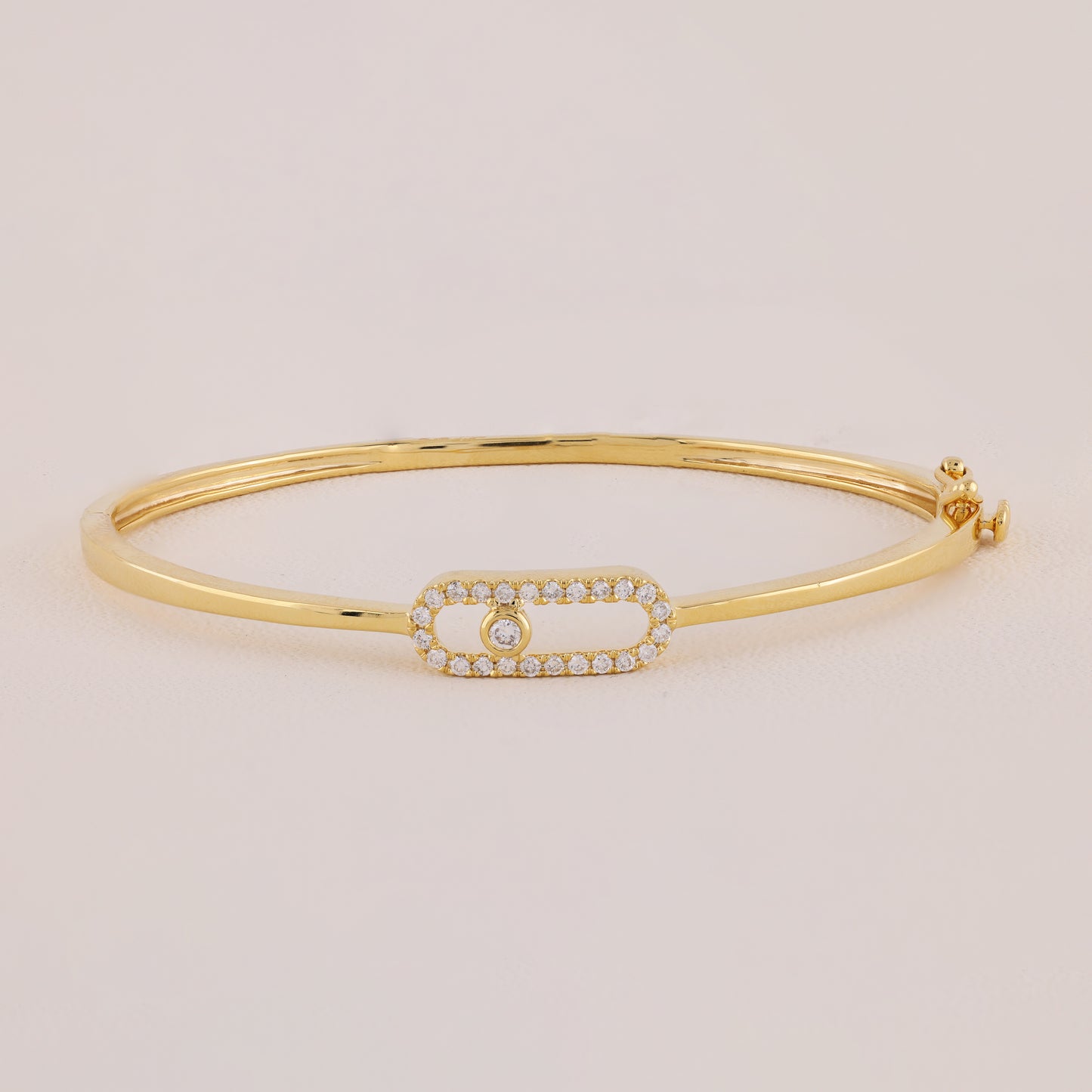 Gold bracelet with a smaall diamond on a beige background