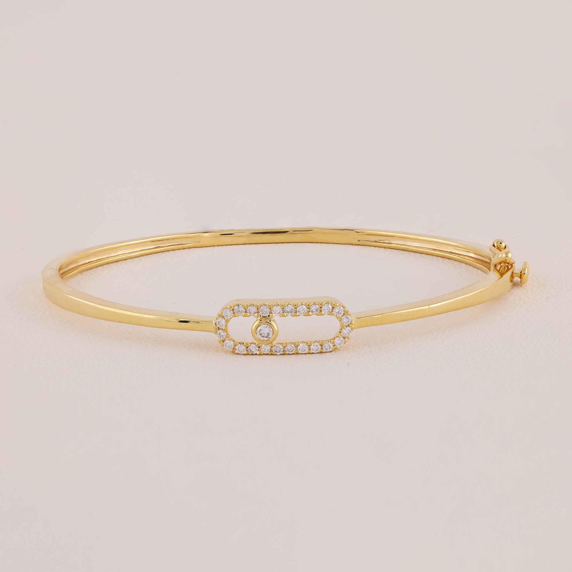 Gold bracelet with a smaall diamond on a beige background