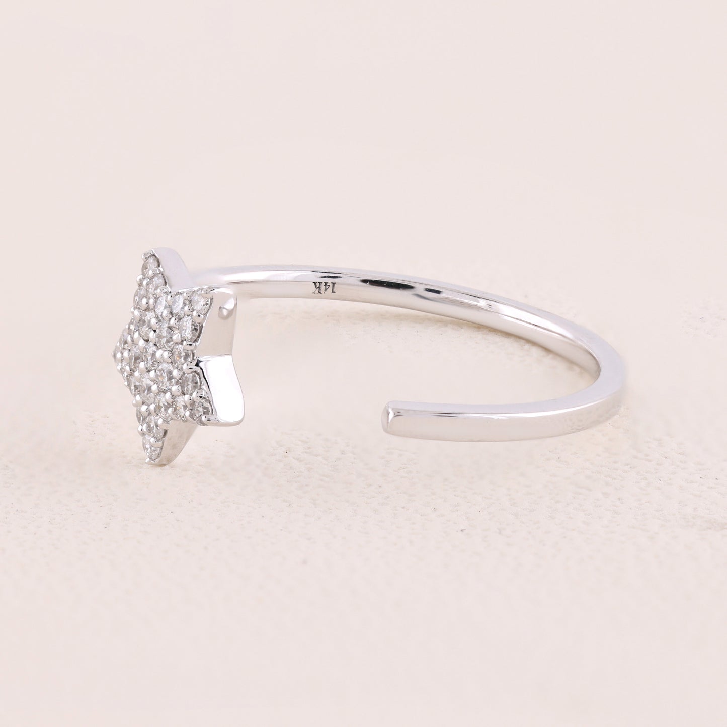 Silver ring with a small diamond on a light pink background