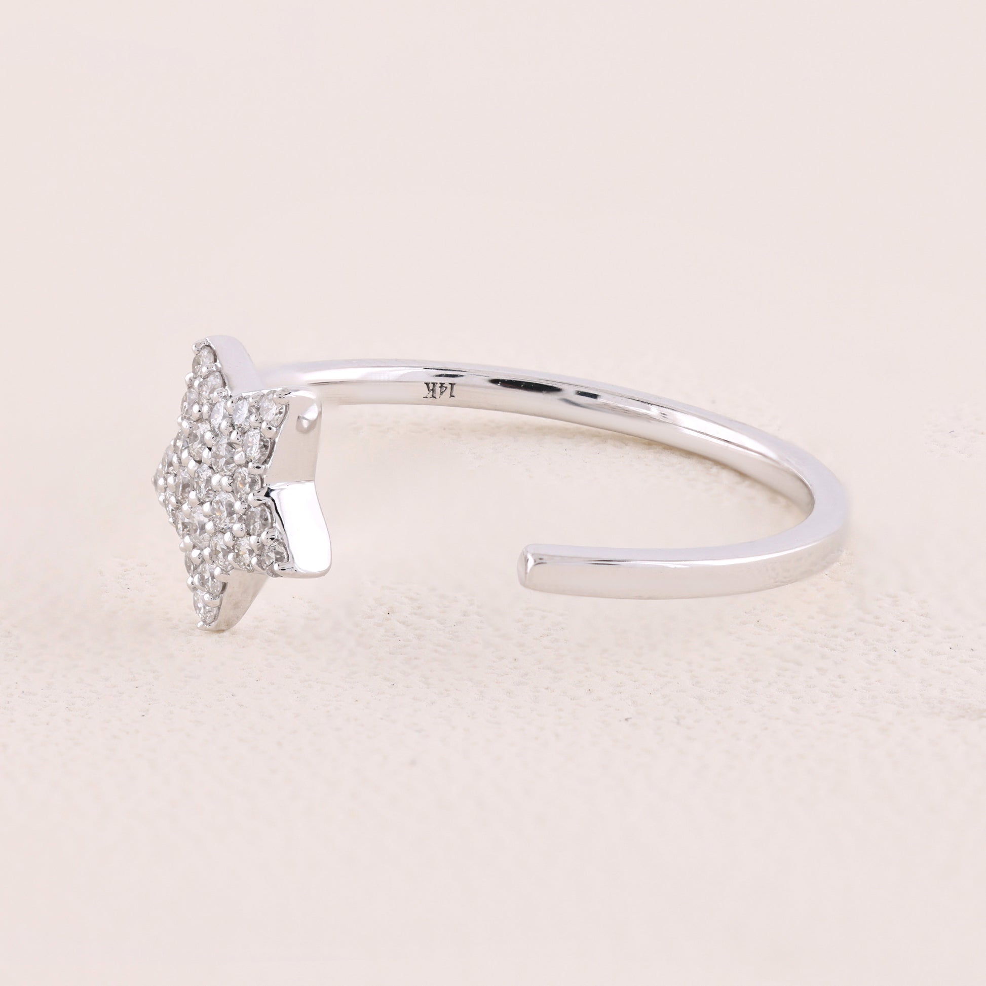 Silver ring with a small diamond on a light pink background