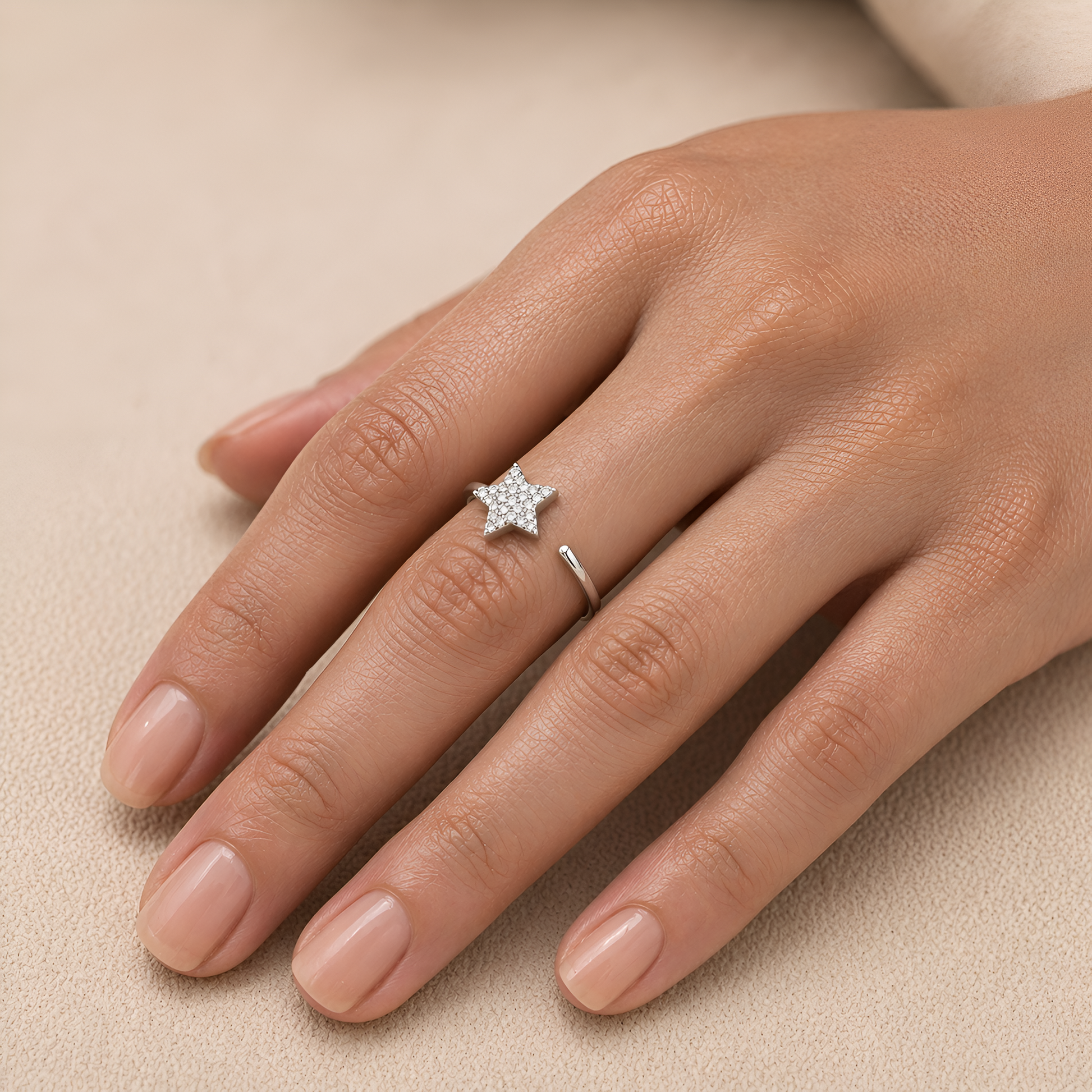 Hand wearing a rose gold ring with diamonds on a beige background