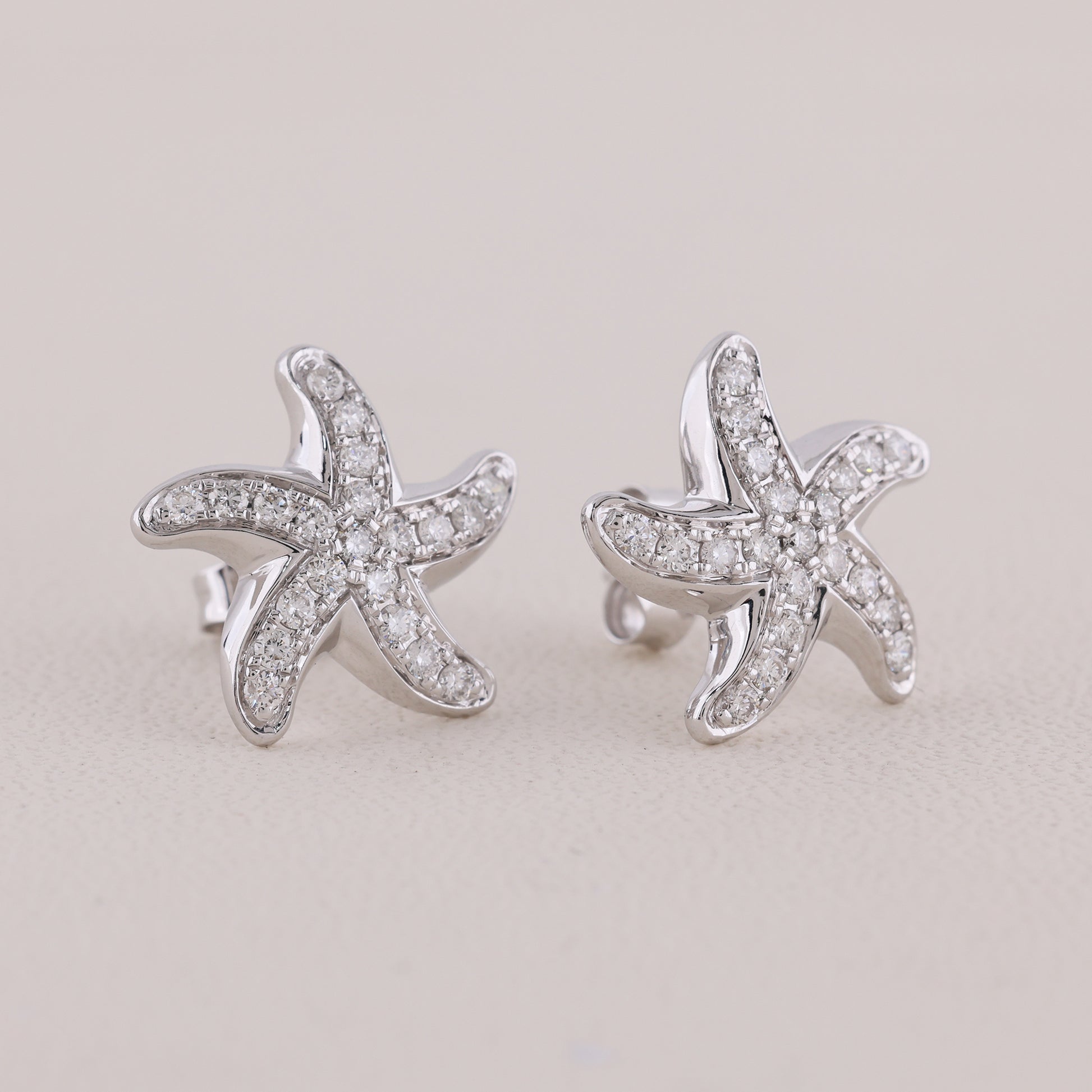 Starfish-shaped earrings with diamond accents on a light gray background