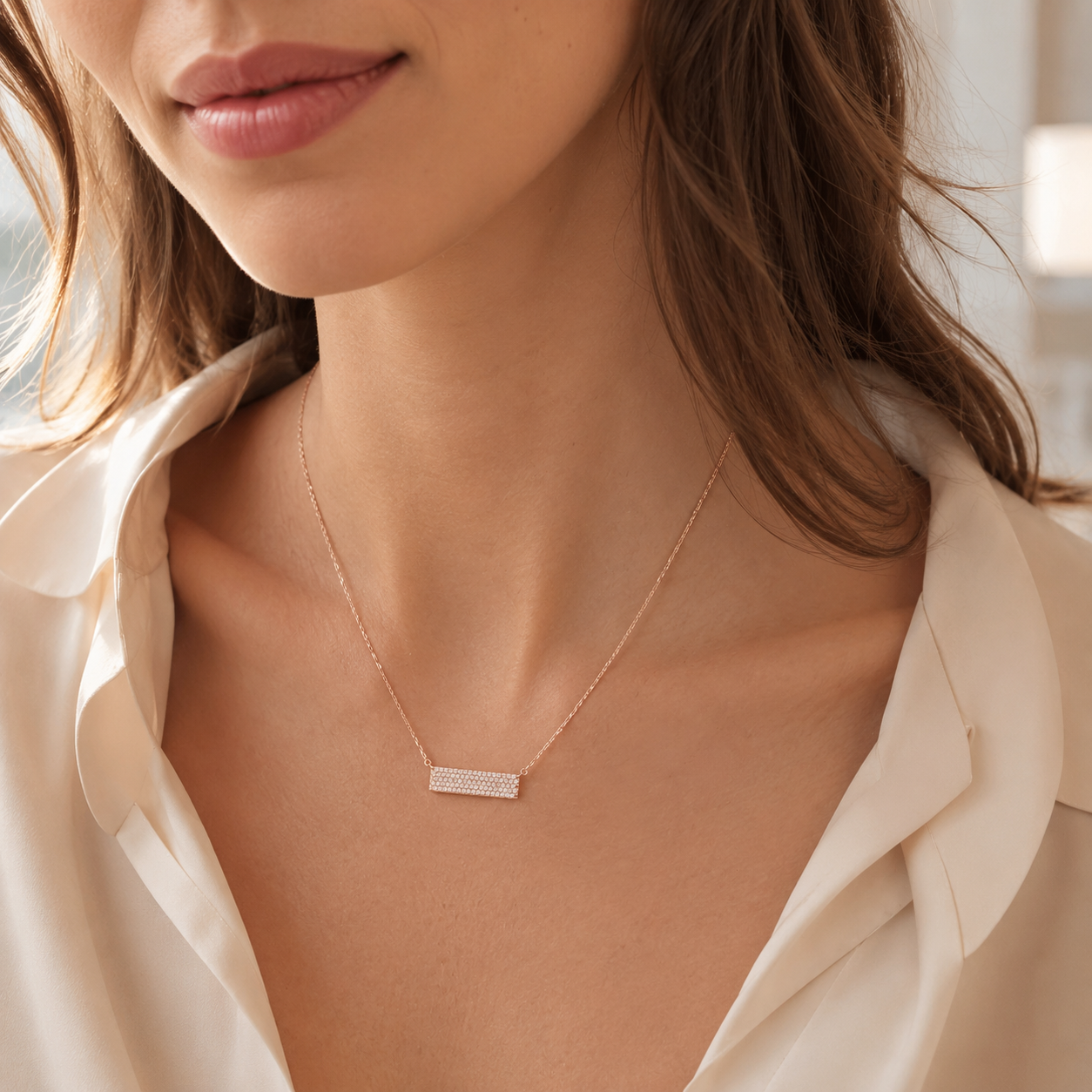 Close-up of a woman wearing a delicate gold necklace with a bar pendant.