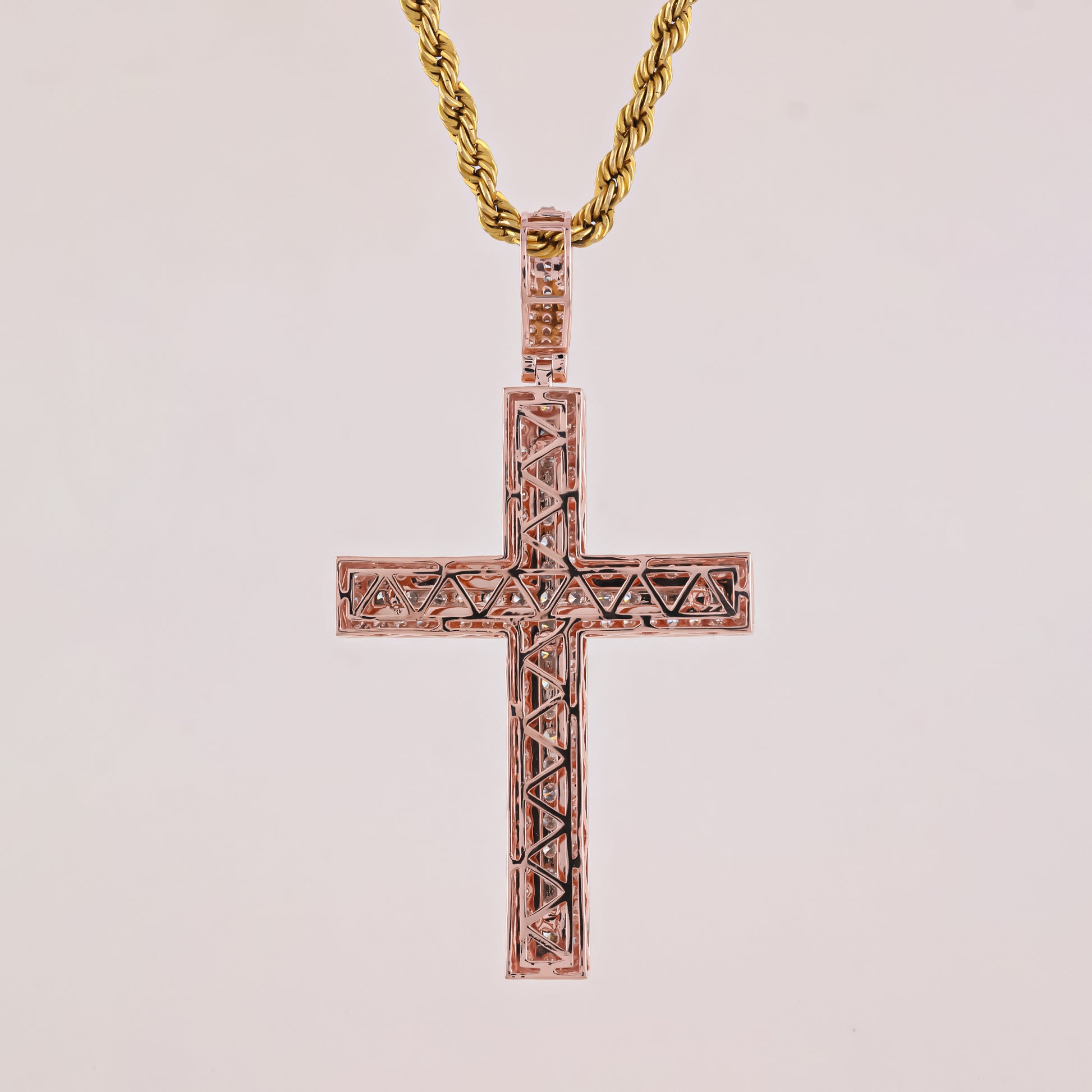 Rose gold cross pendant on a light pink background