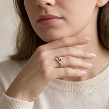Close-up of a person wearing a ring with a 'Y' design on a neutral background