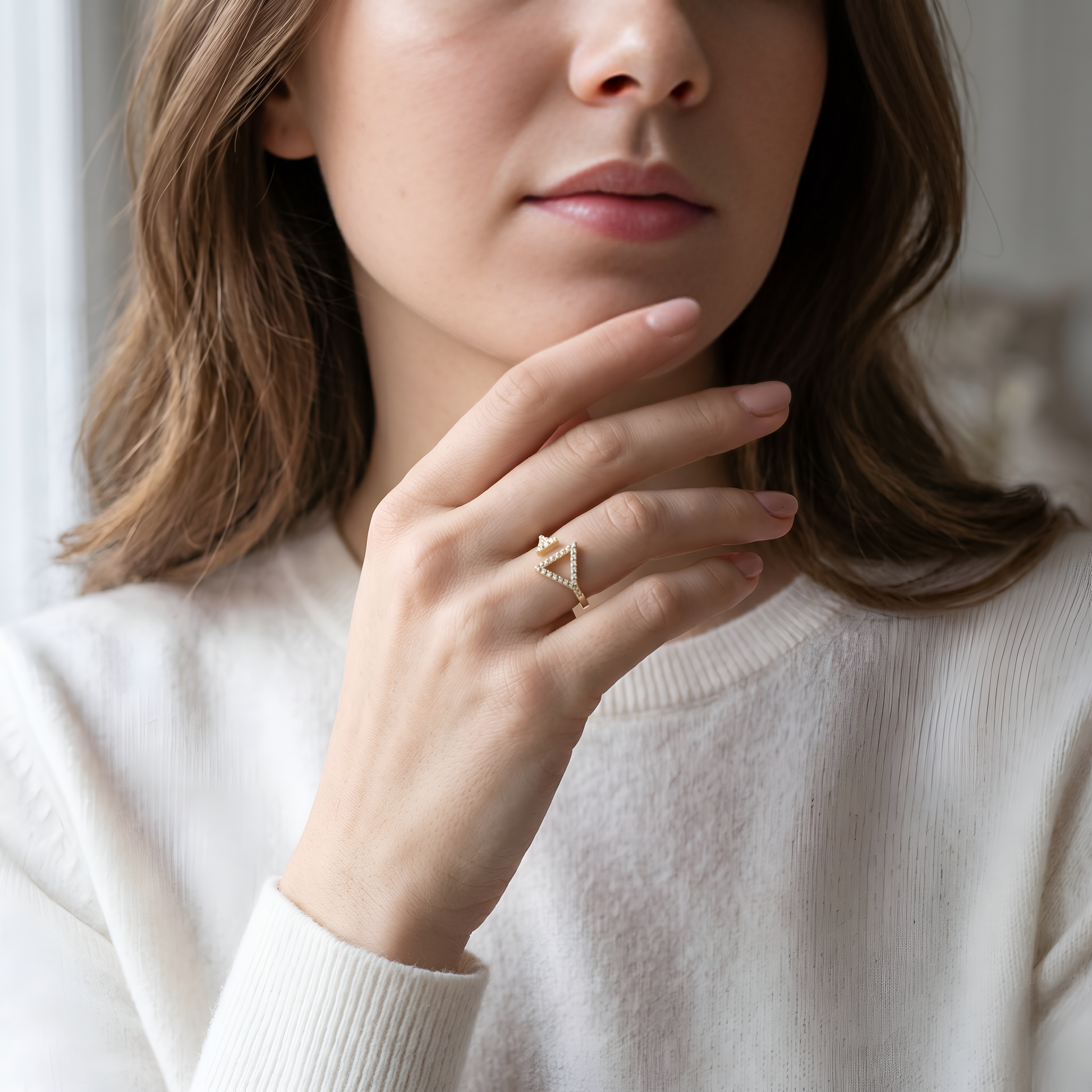 Silver ring with a diamond on a person's finger against a beige background