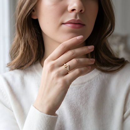 Silver ring with a diamond on a person's finger against a beige background