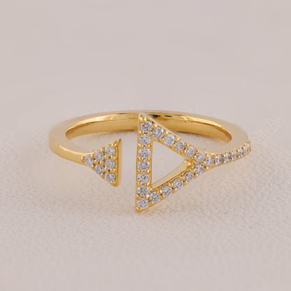 Gold ring with triangular design and embedded diamonds on a beige background
