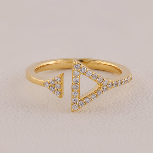 Gold ring with triangular design and embedded diamonds on a beige background