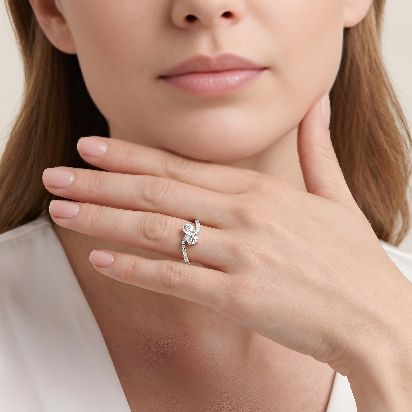 Close-up of a woman's hand wearing a diamond ring, with a neutral background