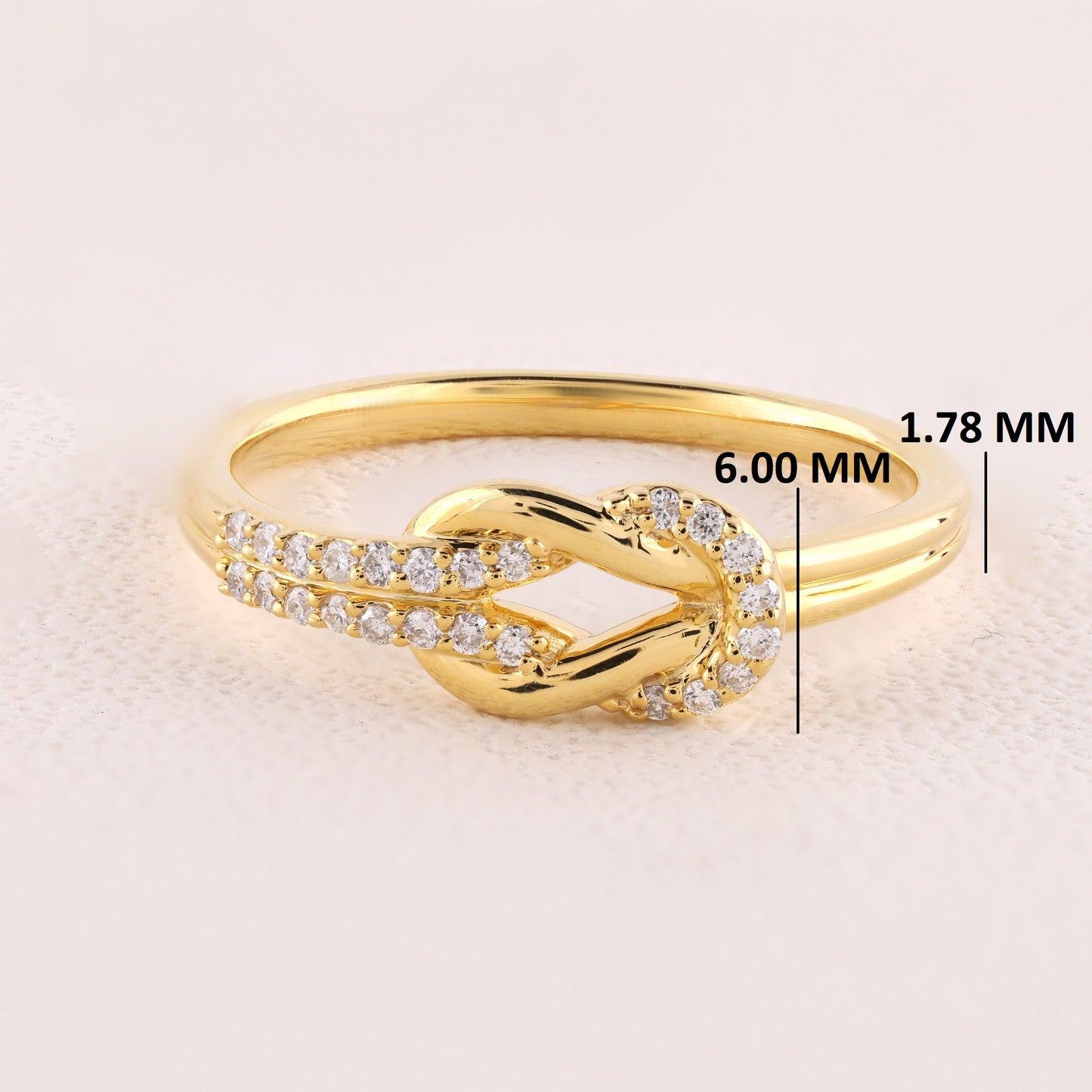 Gold ring with diamond accents on a light beige background, showing measurements.