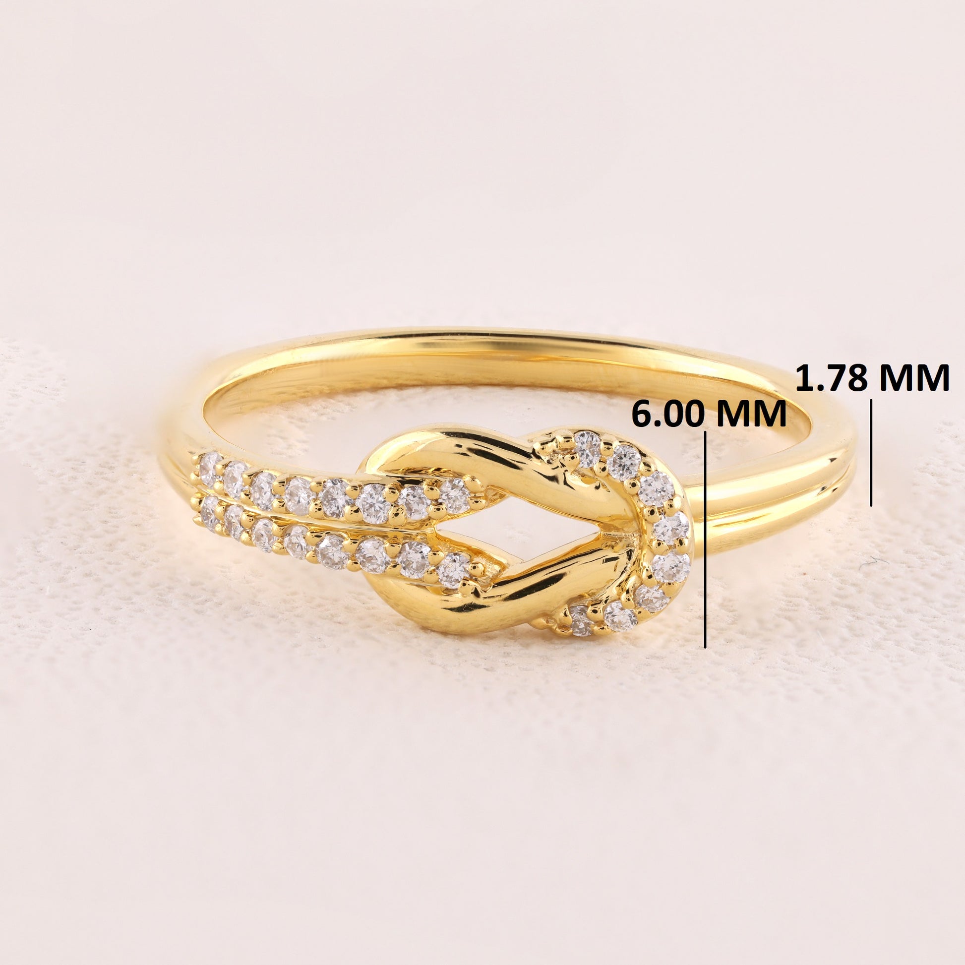 Gold ring with diamond accents on a light beige background, showing measurements.