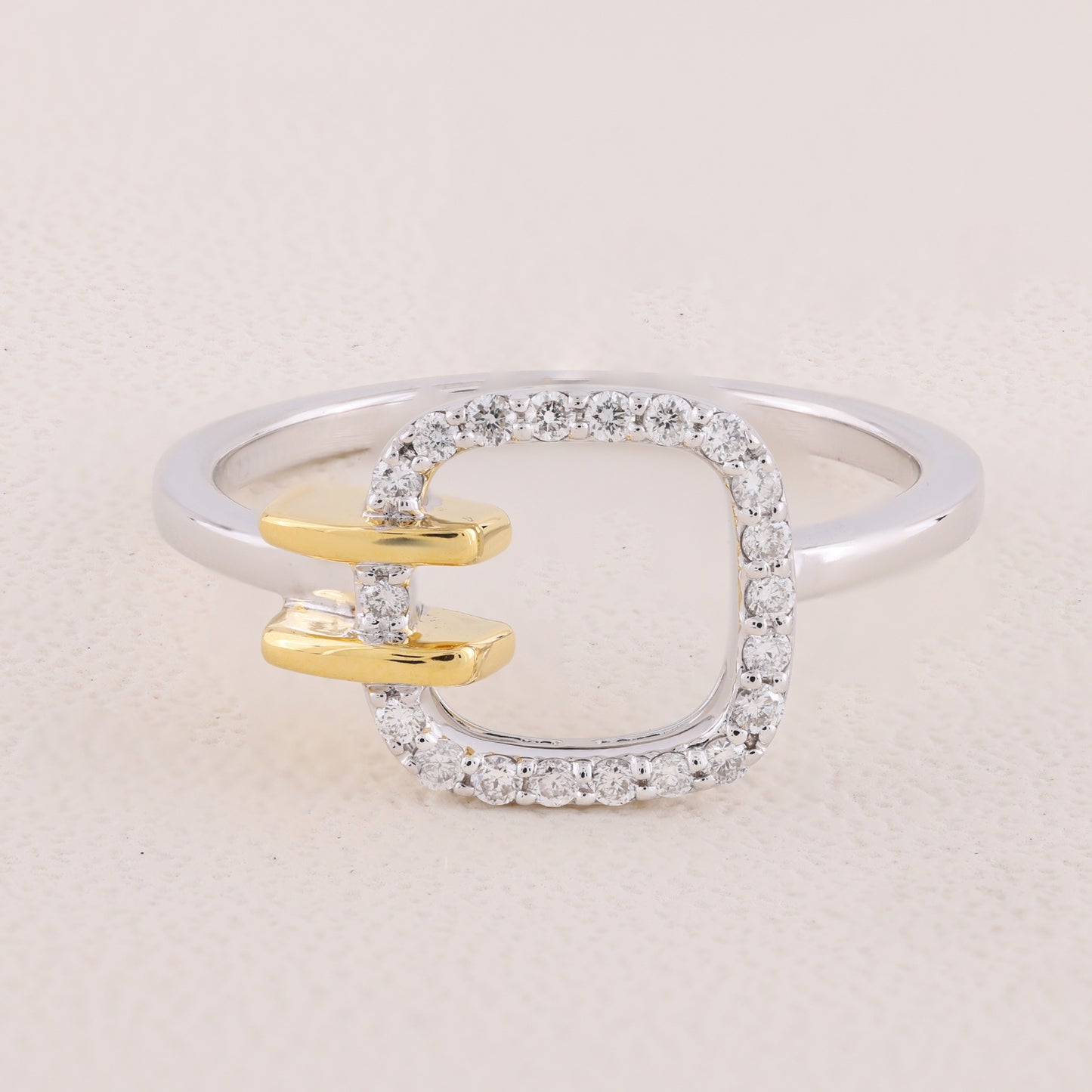 Silver ring with gold accents and diamond-like stones on a light beige background
