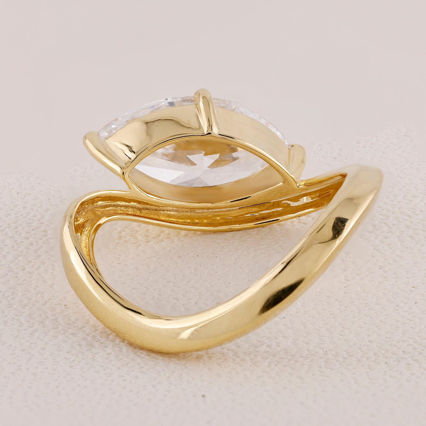 Gold ring with a clear gemstone on a beige background