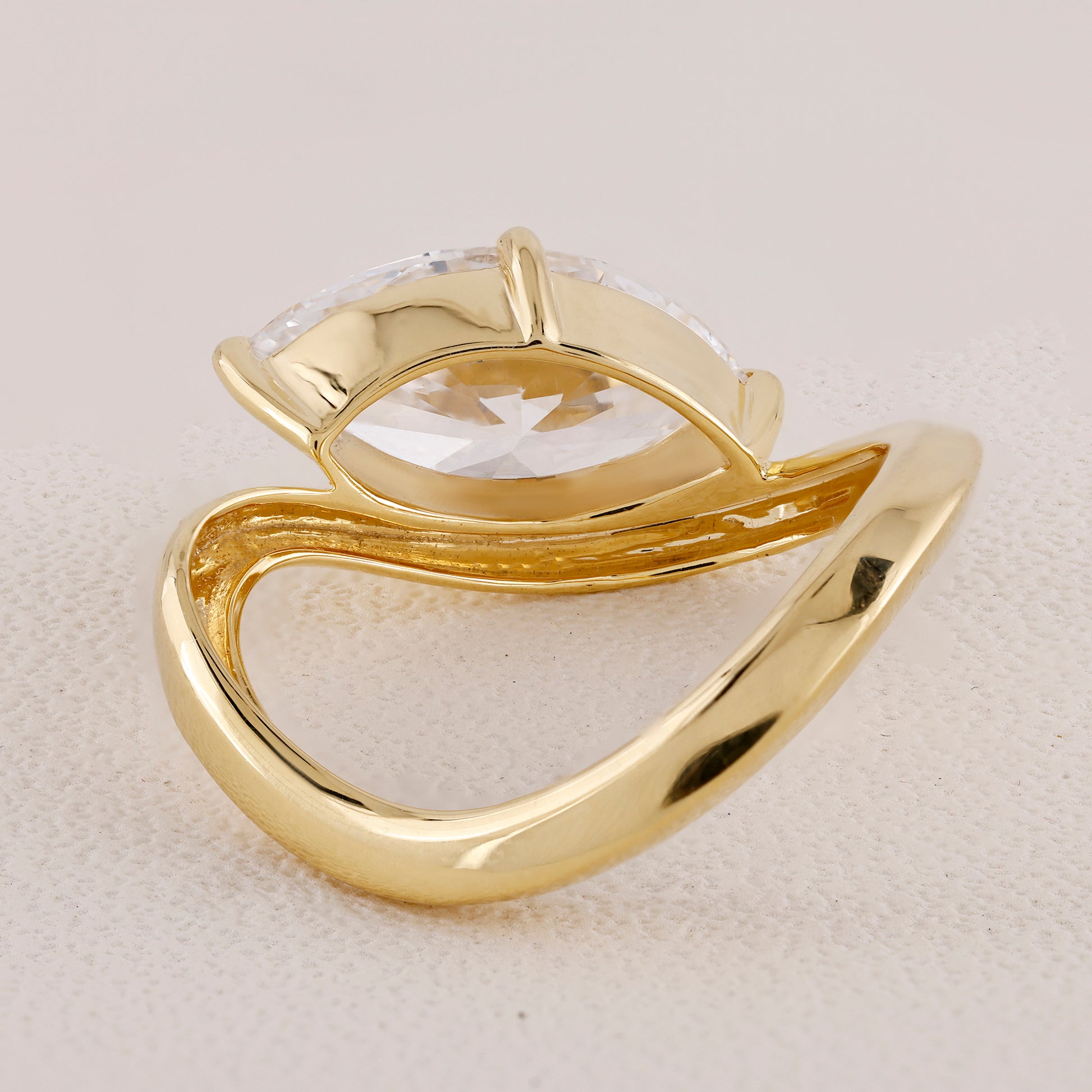 Gold ring with a clear gemstone on a beige background