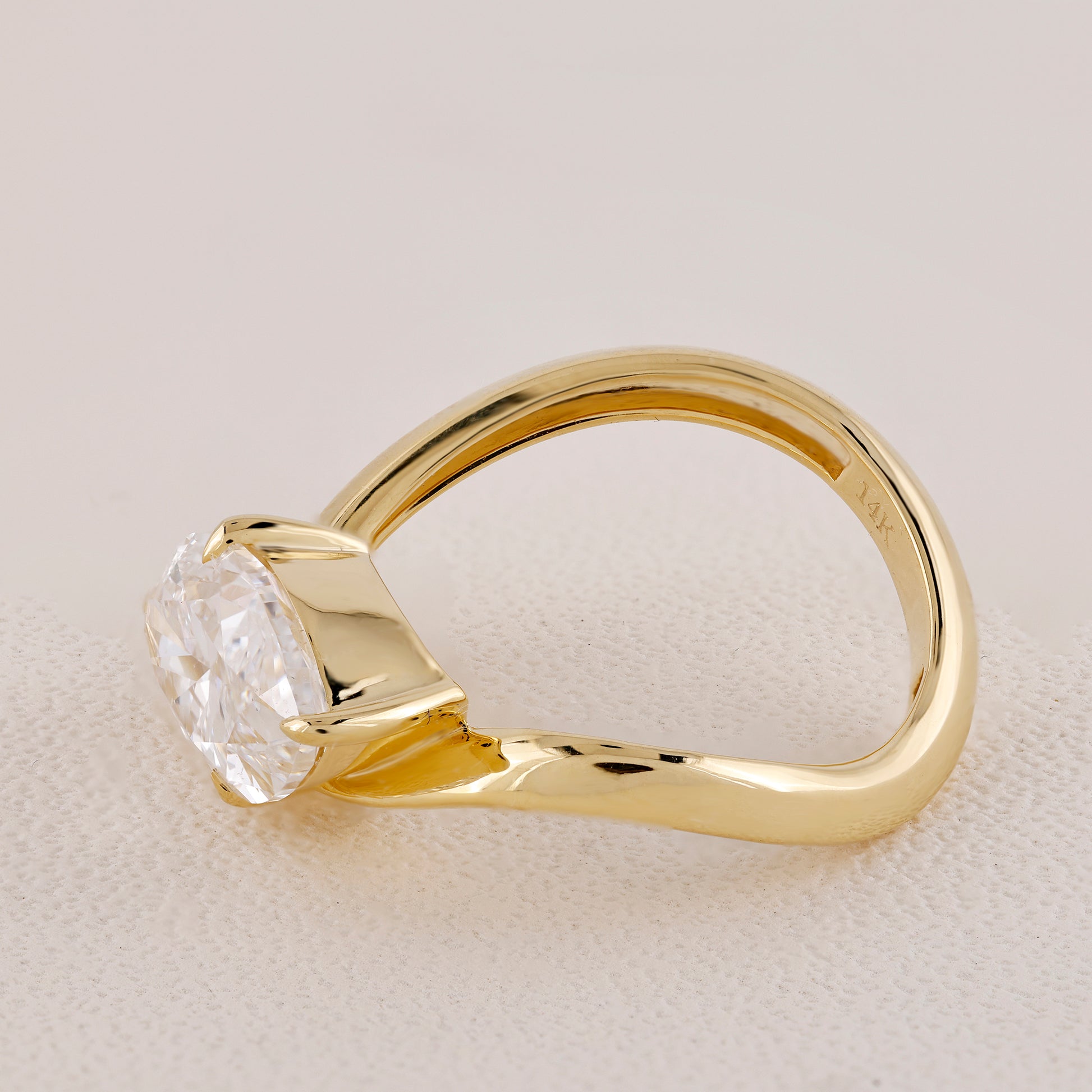 Gold ring with a diamond on a light beige background