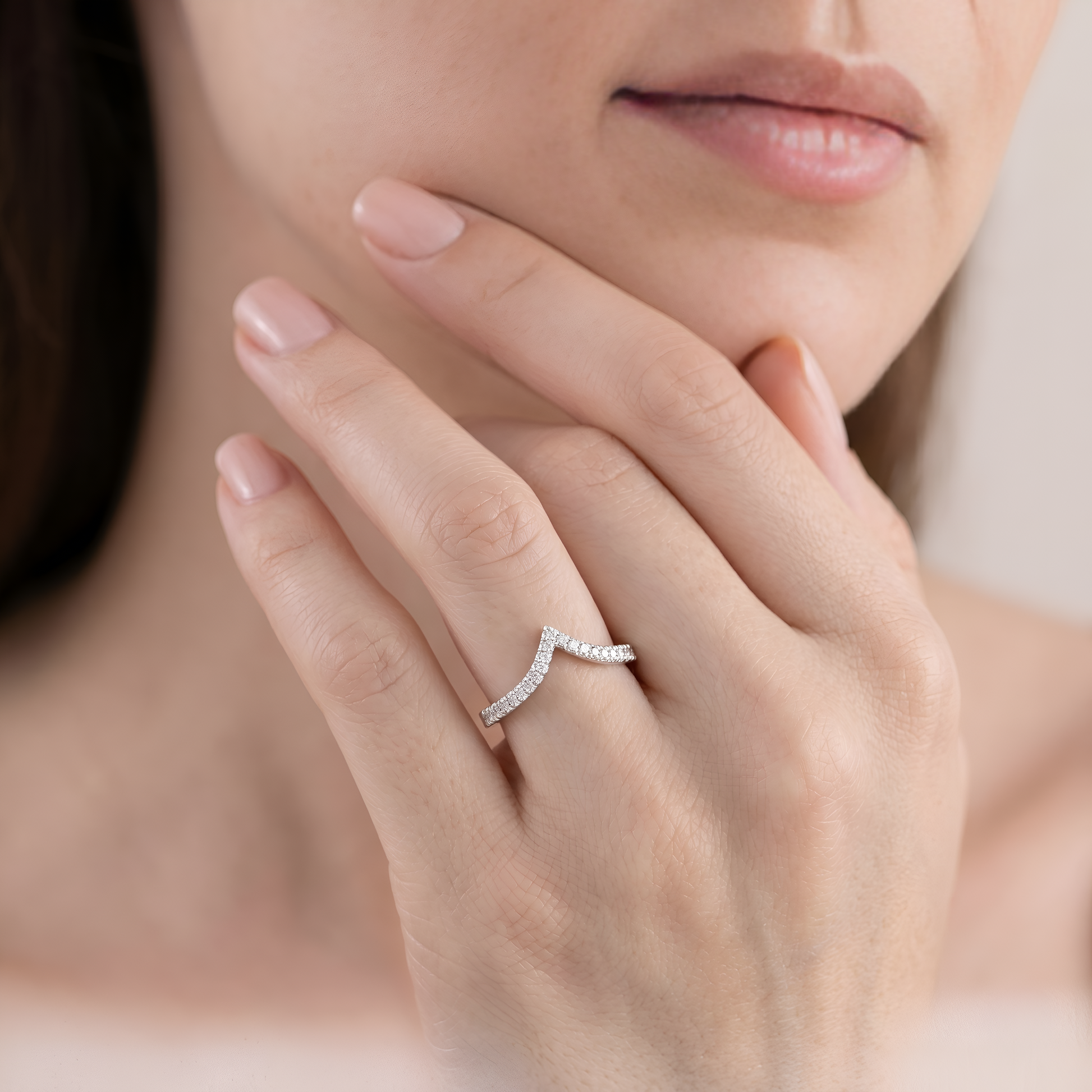 Close-up of a hand wearing a diamond ring with a blurred background