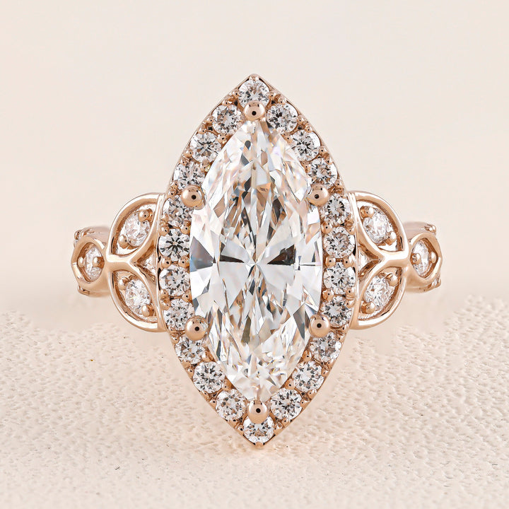 Rose gold ring with a large marquise-shaped diamond and smaller diamonds on a beige background
