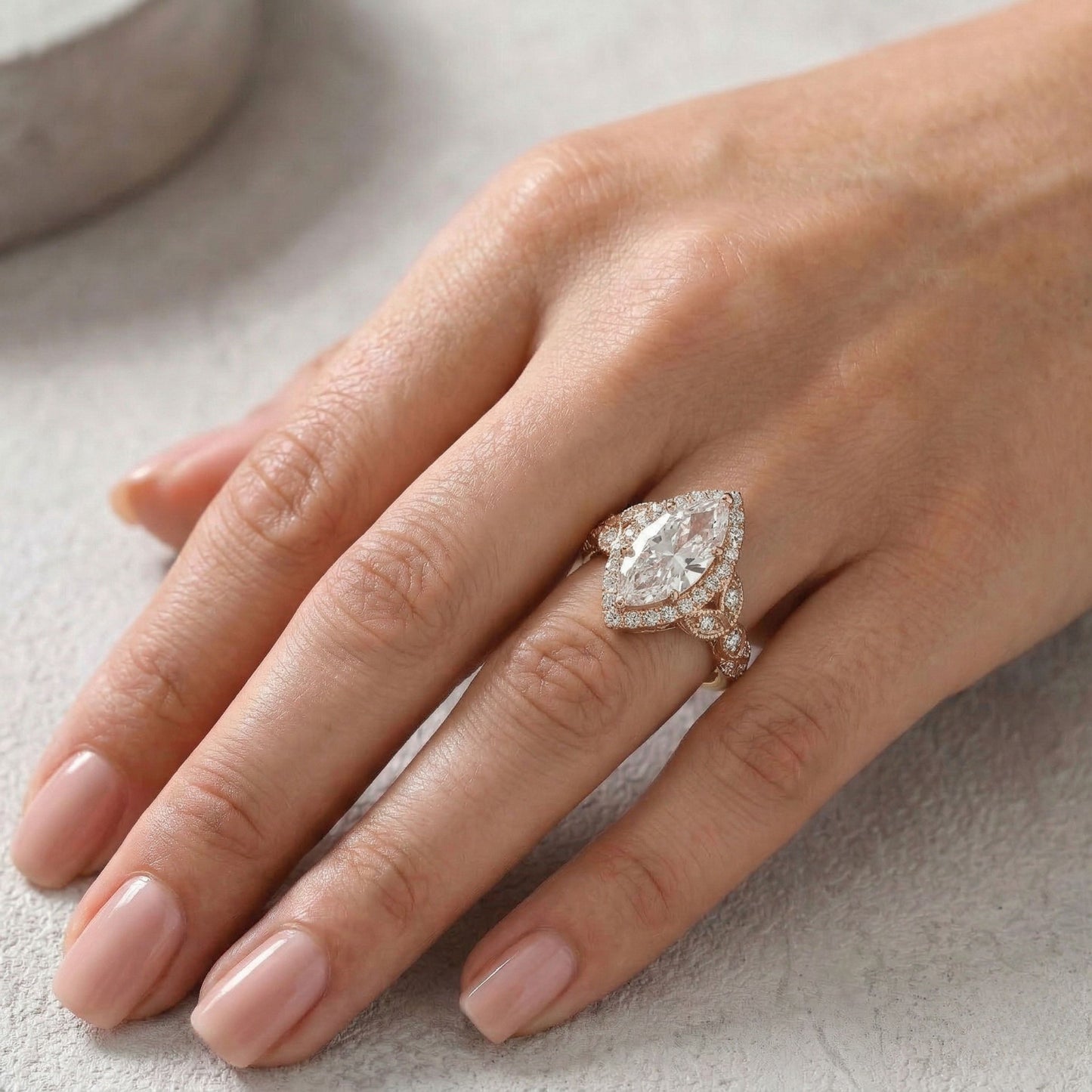 Hand wearing a diamond ring on a light background