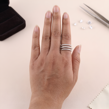 Hand wearing two silver rings on a light background