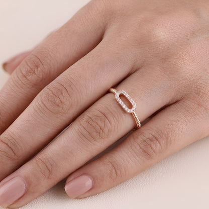 Rose gold ring with diamonds on a hand against a beige background