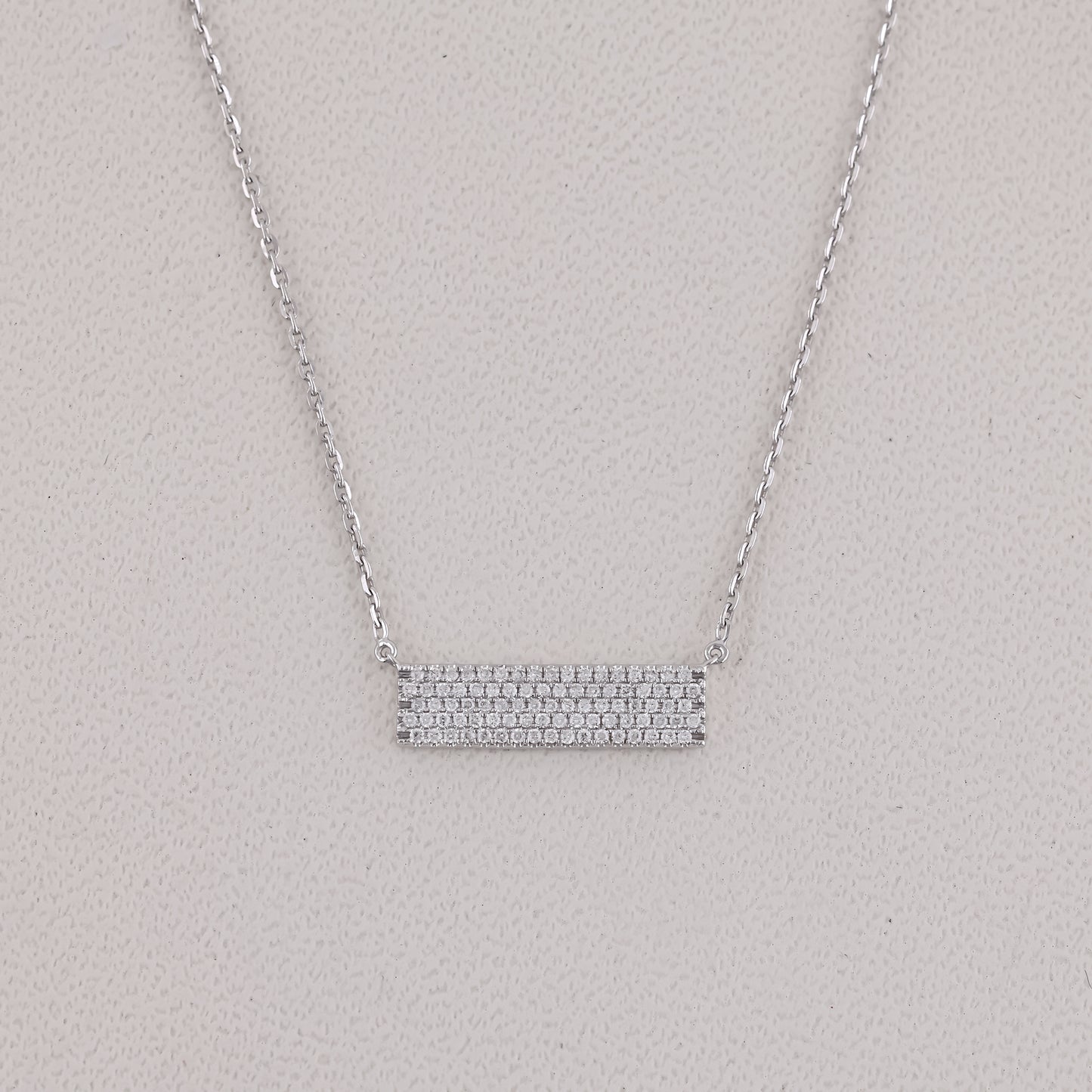 Silver necklace with a bar pendant on a light gray background