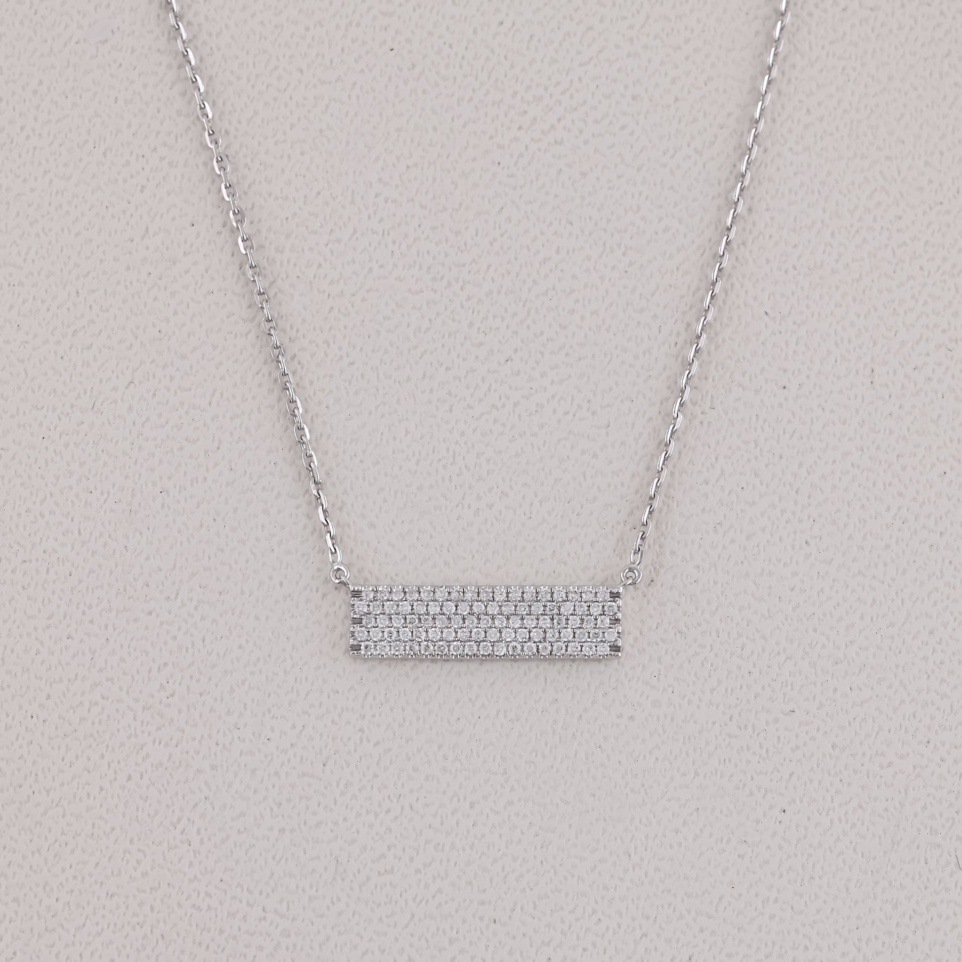 Silver necklace with a bar pendant on a light gray background